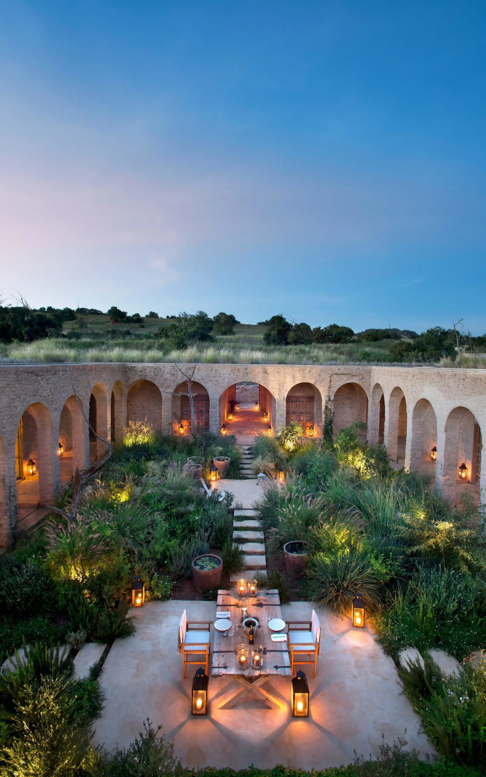 Arijiju's arched courtyard glows at dusk, with lanterns, outdoor seating, and gardens in Laikipia, Kenya.