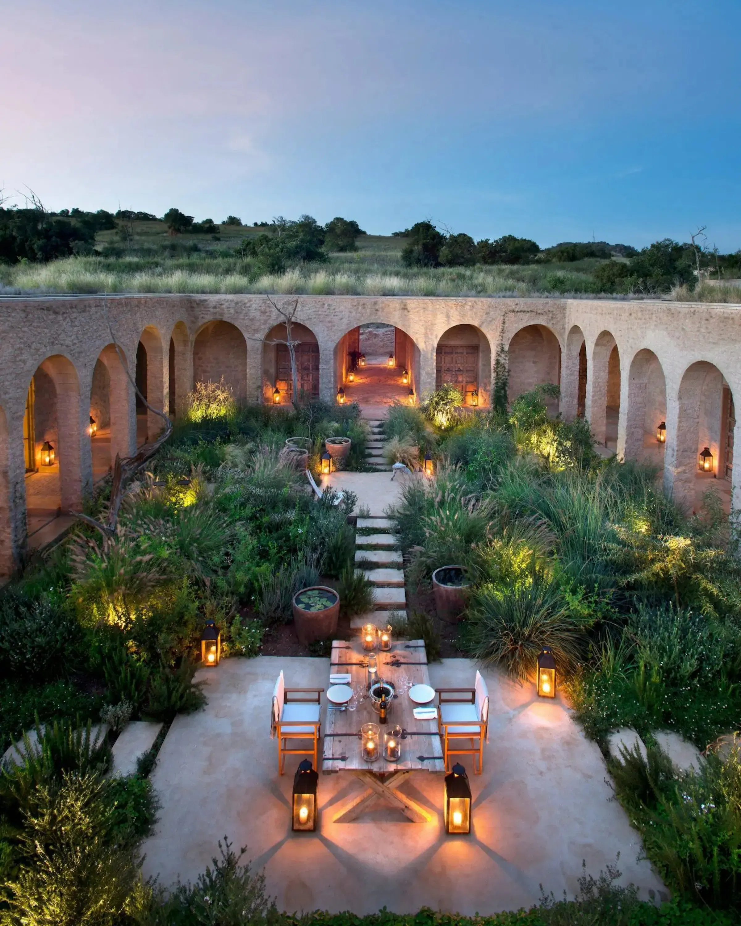 Arijiju's arched courtyard glows at dusk, with lanterns, outdoor seating, and gardens in Laikipia, Kenya.