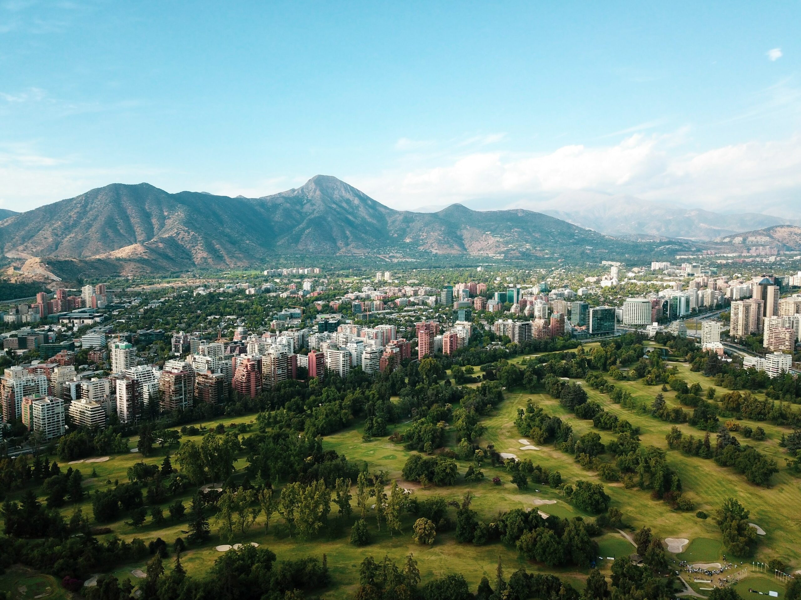 Santiago's skyline stretches beneath the Andes, with towers and apartment blocks lit by clear afternoon sun.