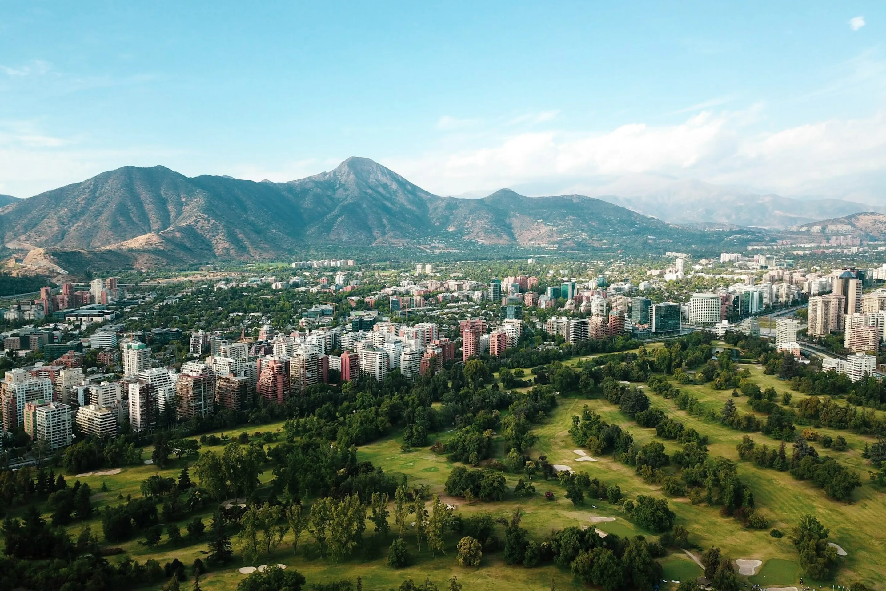 Santiago's skyline stretches beneath the Andes, with towers and apartment blocks lit by clear afternoon sun.