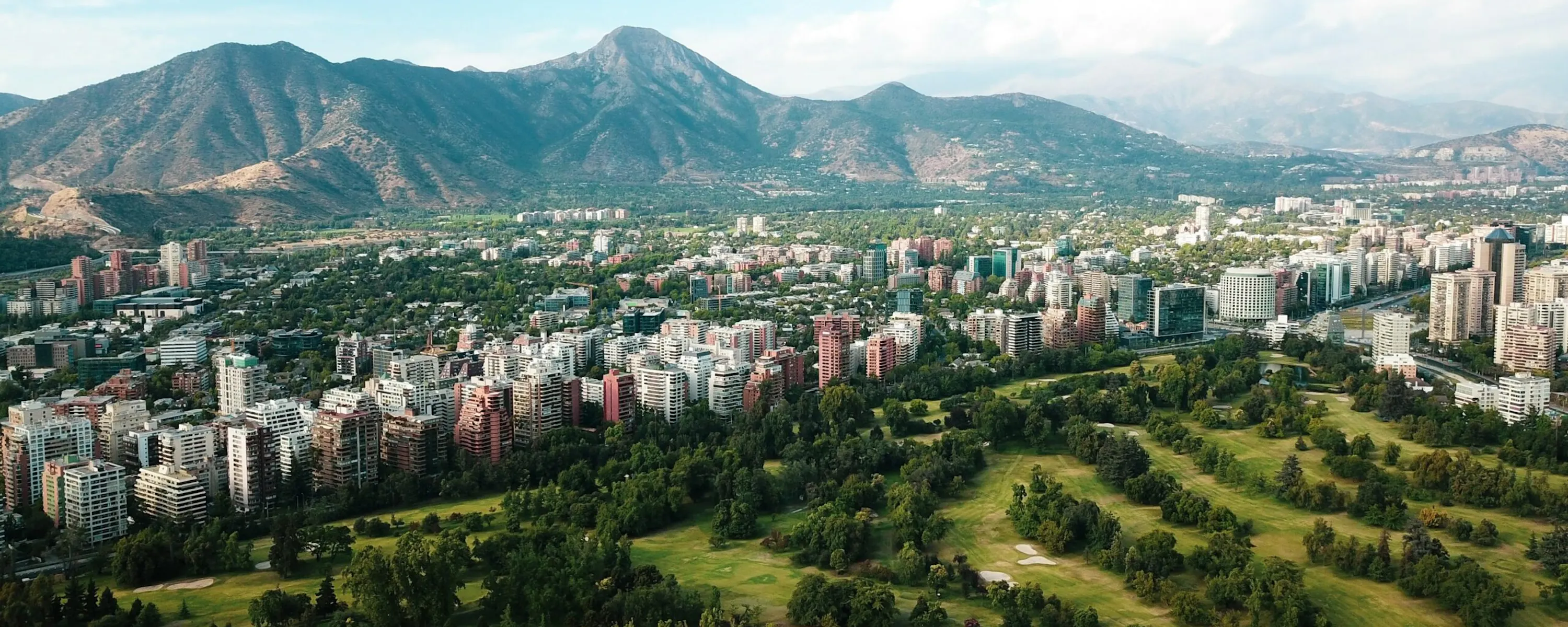 Santiago's skyline stretches beneath the Andes, with towers and apartment blocks lit by clear afternoon sun.
