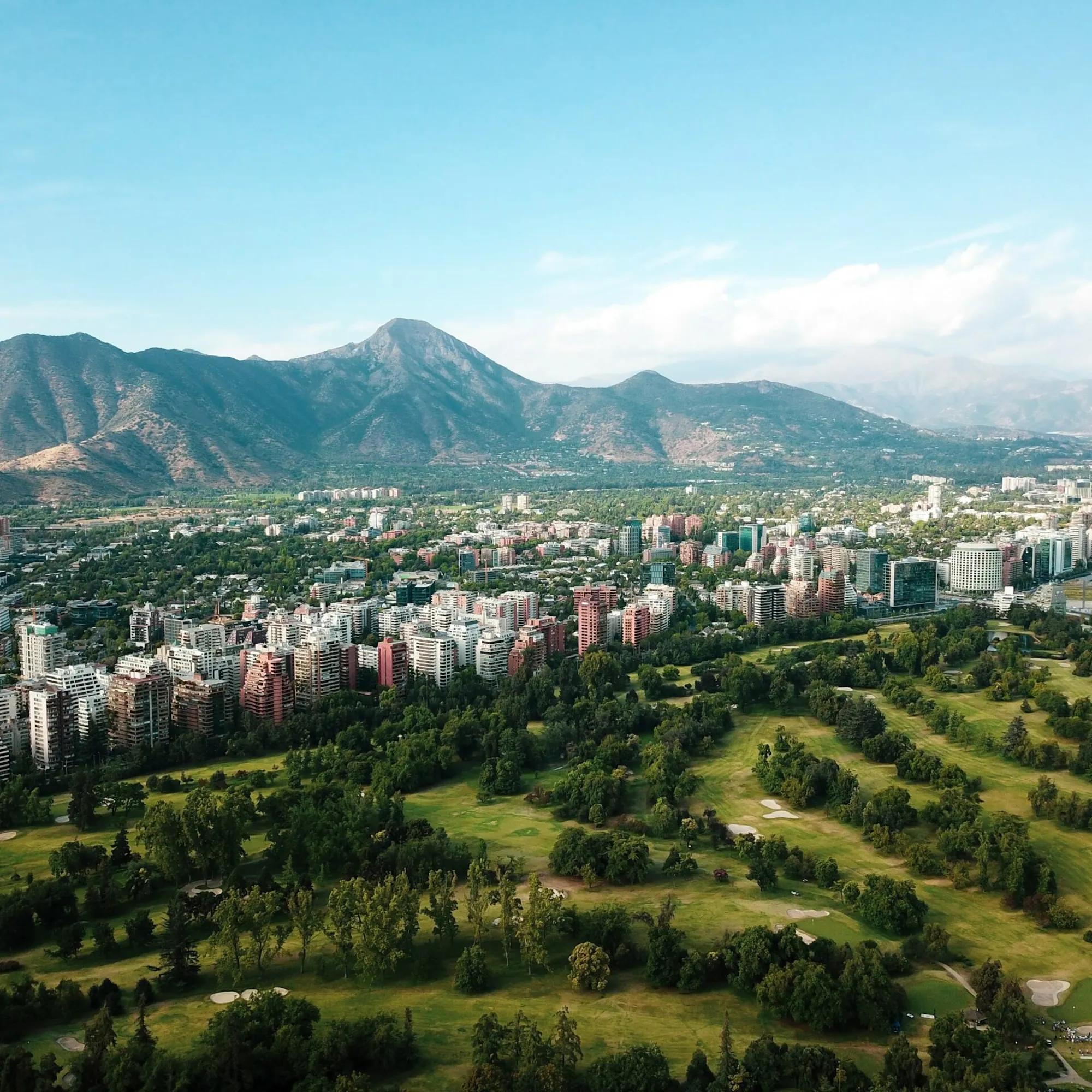Santiago's skyline stretches beneath the Andes, with towers and apartment blocks lit by clear afternoon sun.