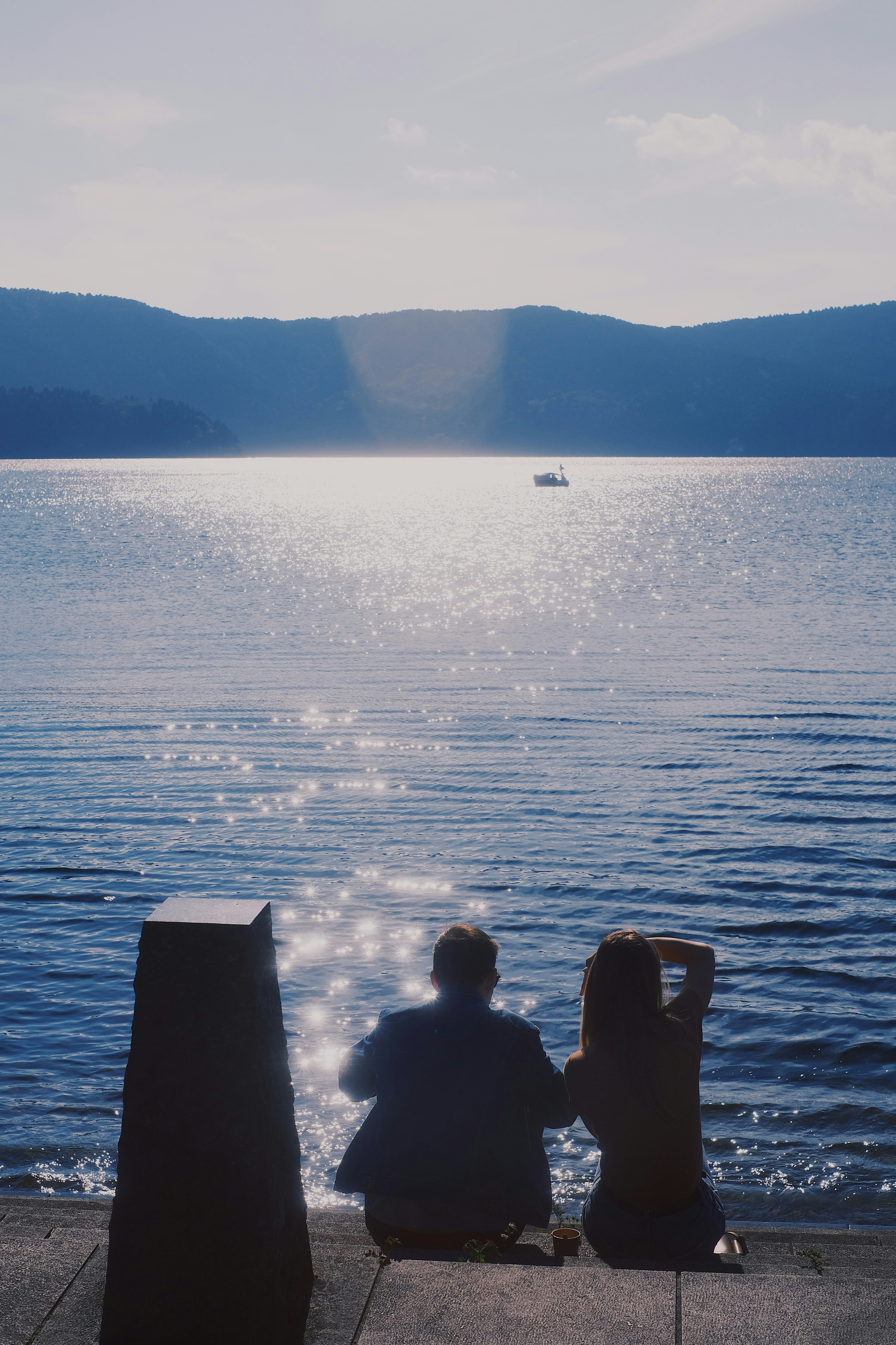 A couple looks out at a peaceful lakeside scene in Hakone Japan