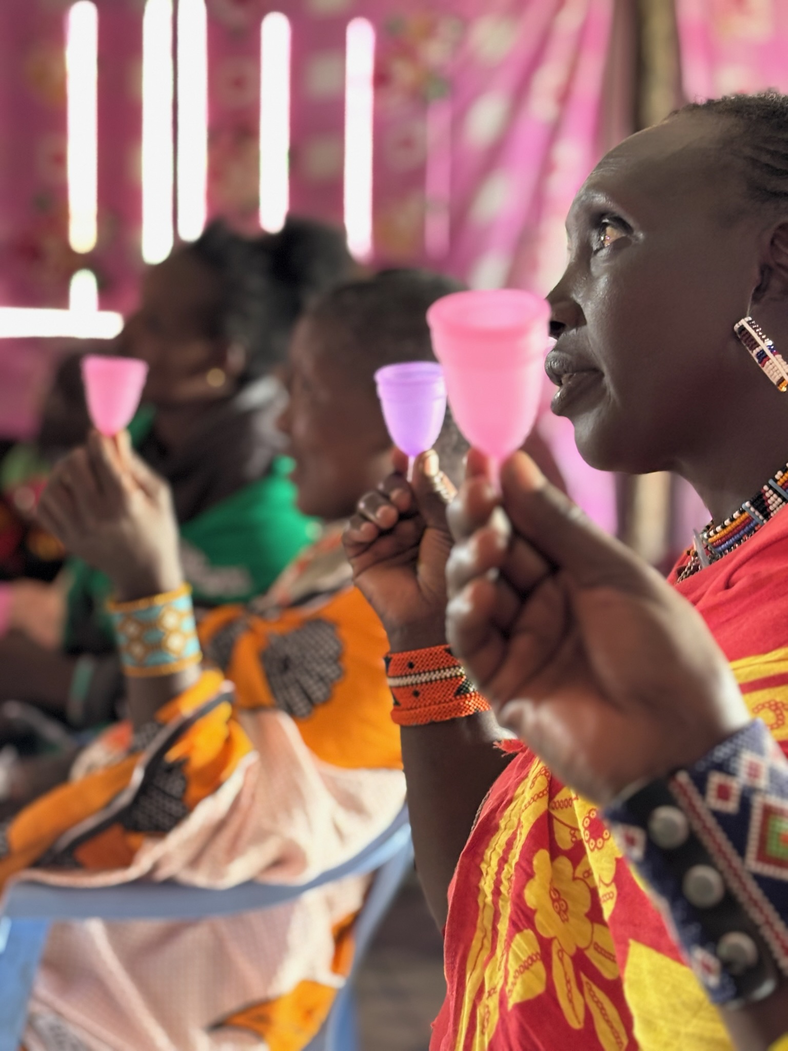 A group of Samburu women holding up menstrual cups, Kenya