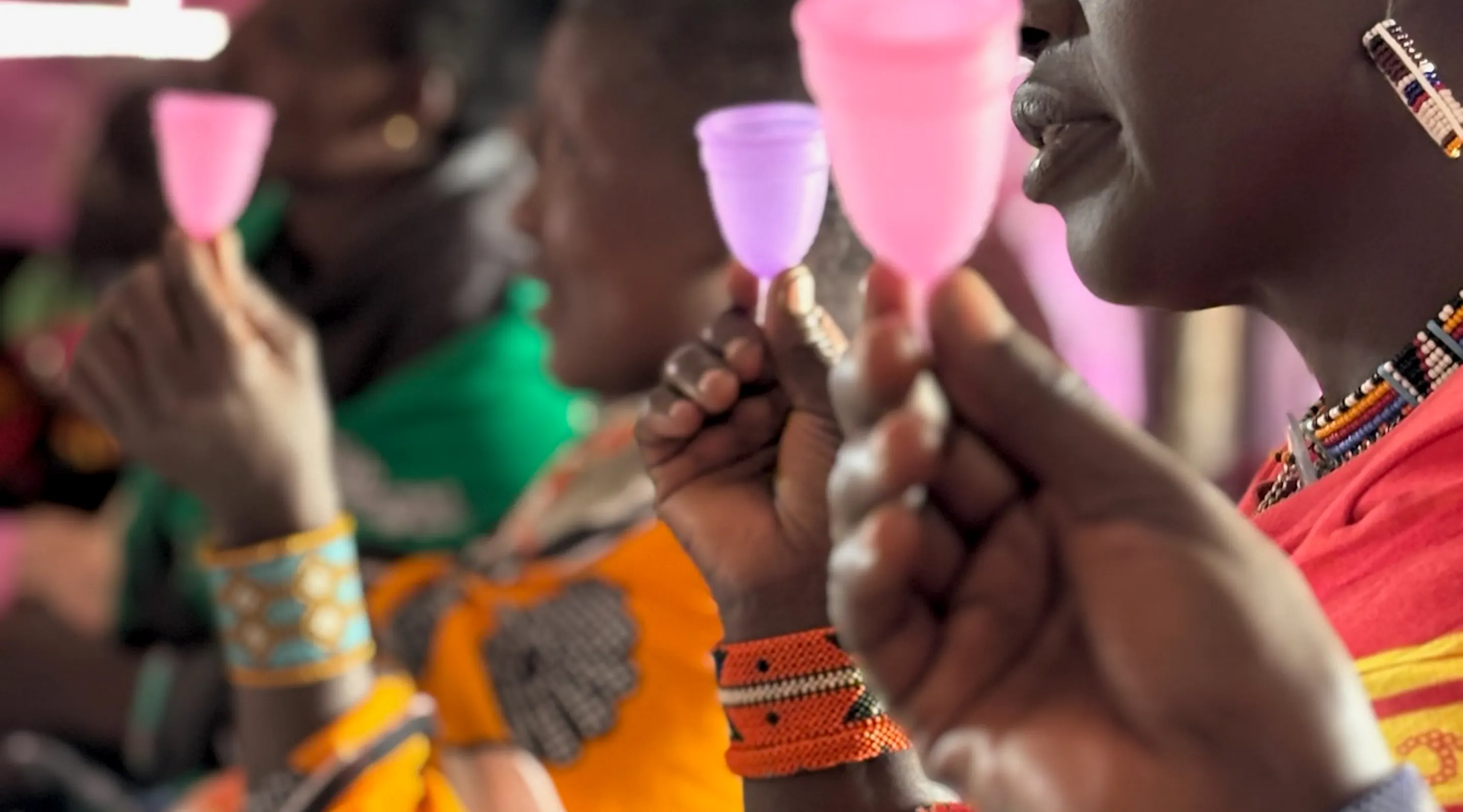 A group of Samburu women holding up menstrual cups, Kenya
