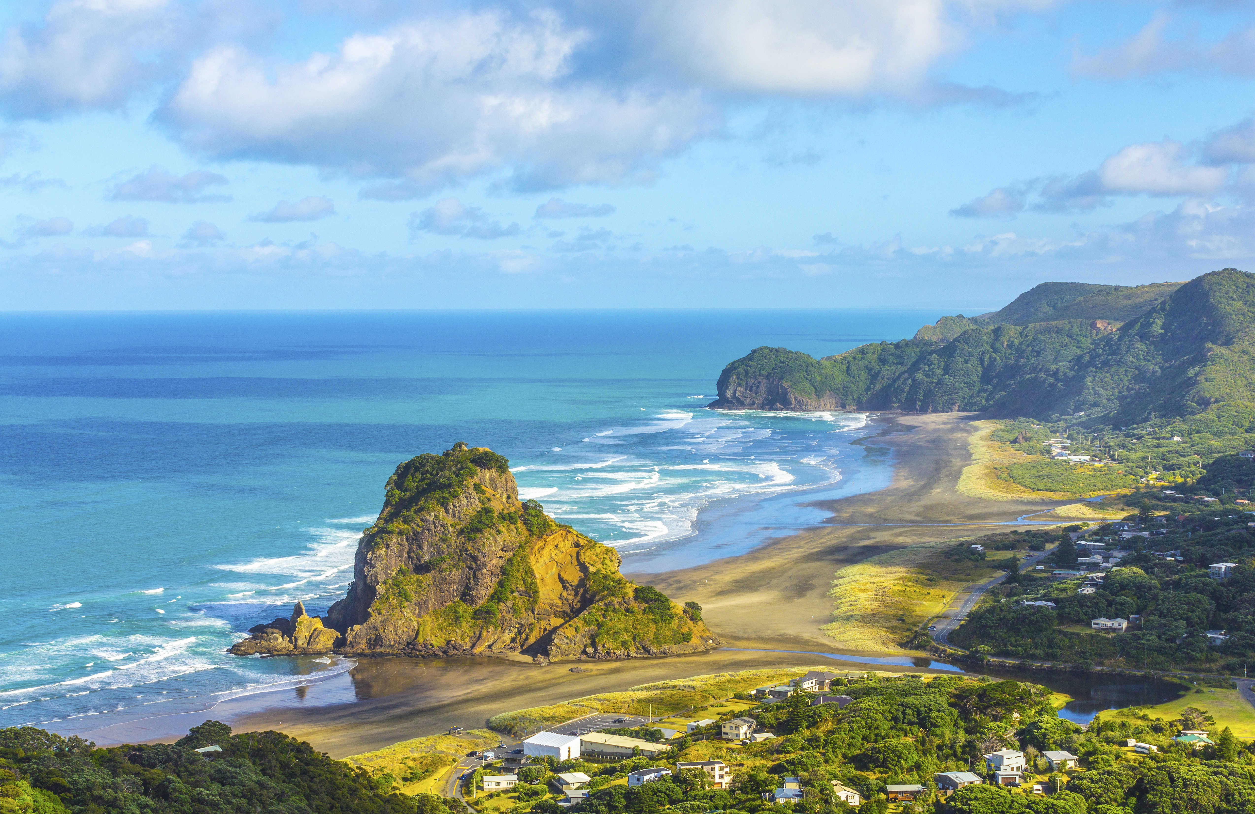 Aerial view of Auckland's coastline with the city skyline and Waitemata Harbour under blue sky.