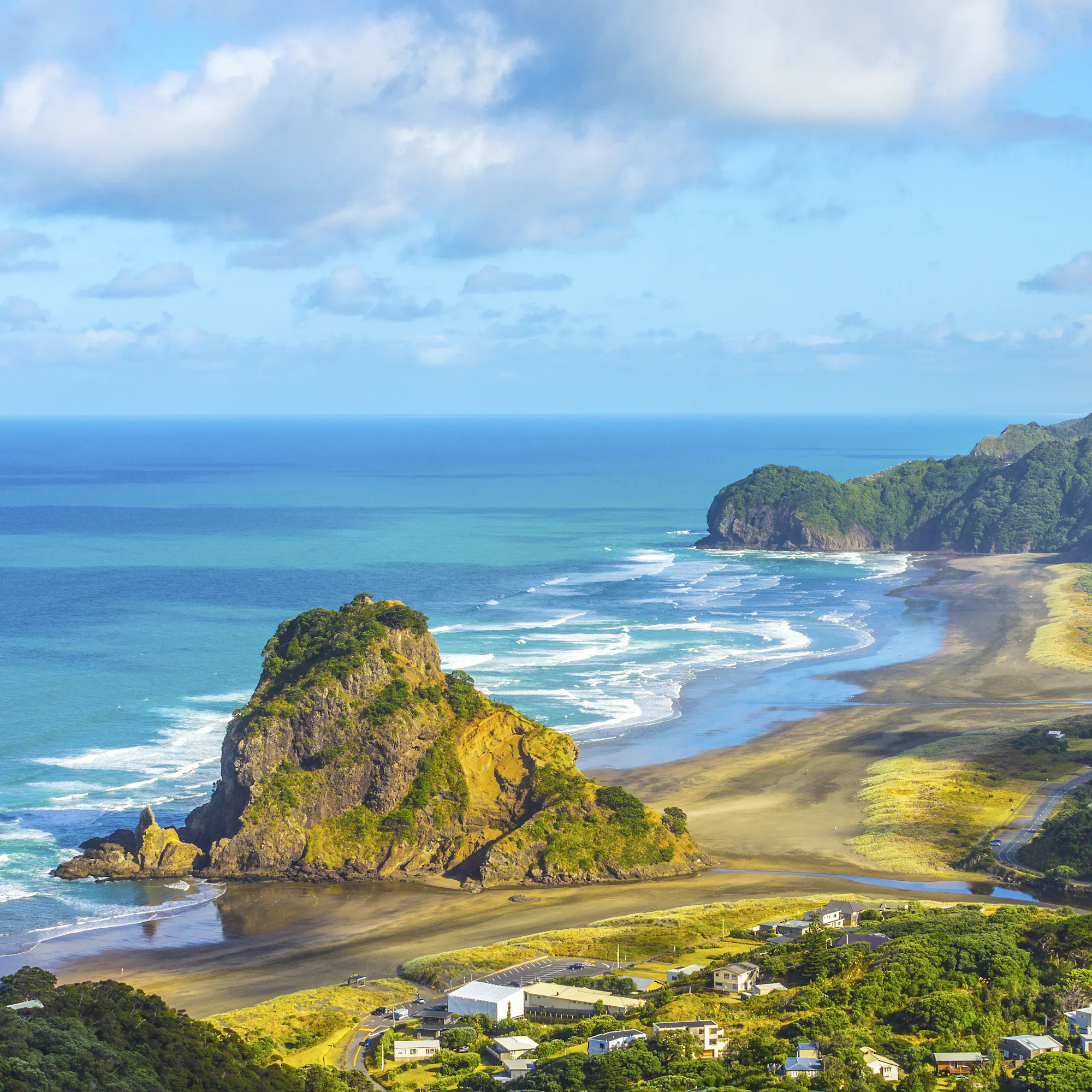 Aerial view of Auckland's coastline with the city skyline and Waitemata Harbour under blue sky.