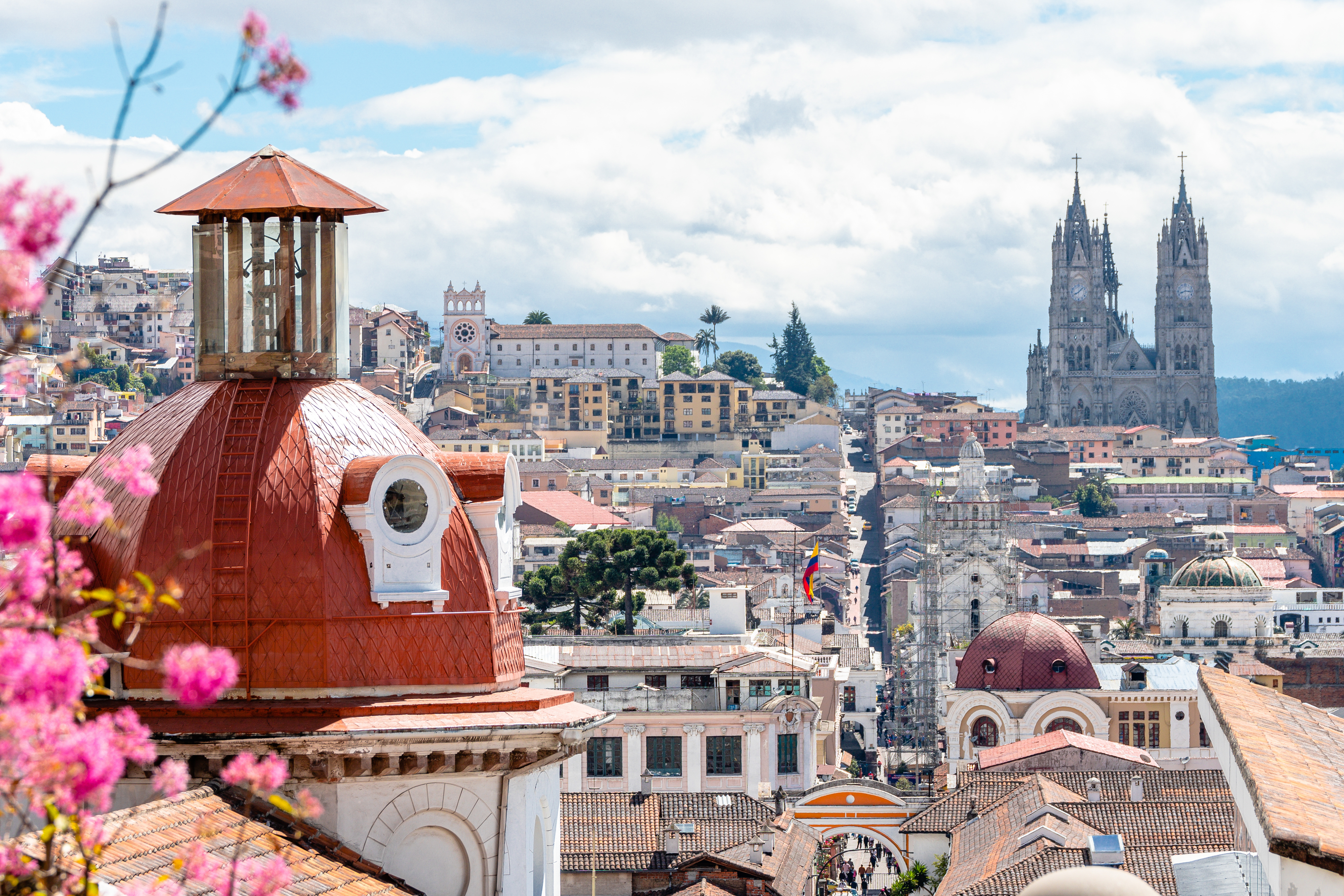 Quito's historic old town spreads across a hillside with the ornate Basilica del Voto Nacional visible.