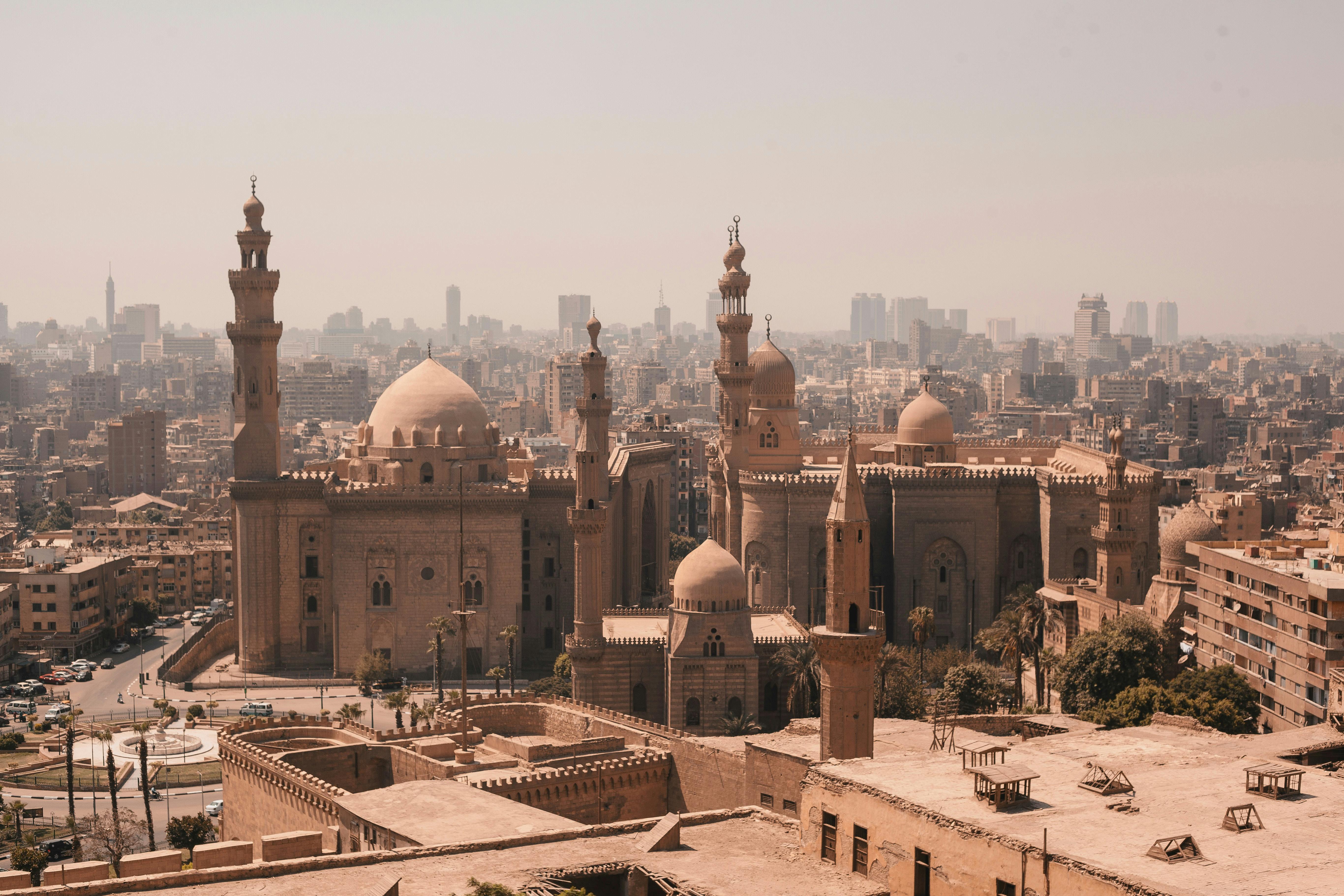A panoramic view of Cairo's dense cityscape with mosques and minarets rising against a hazy sky.