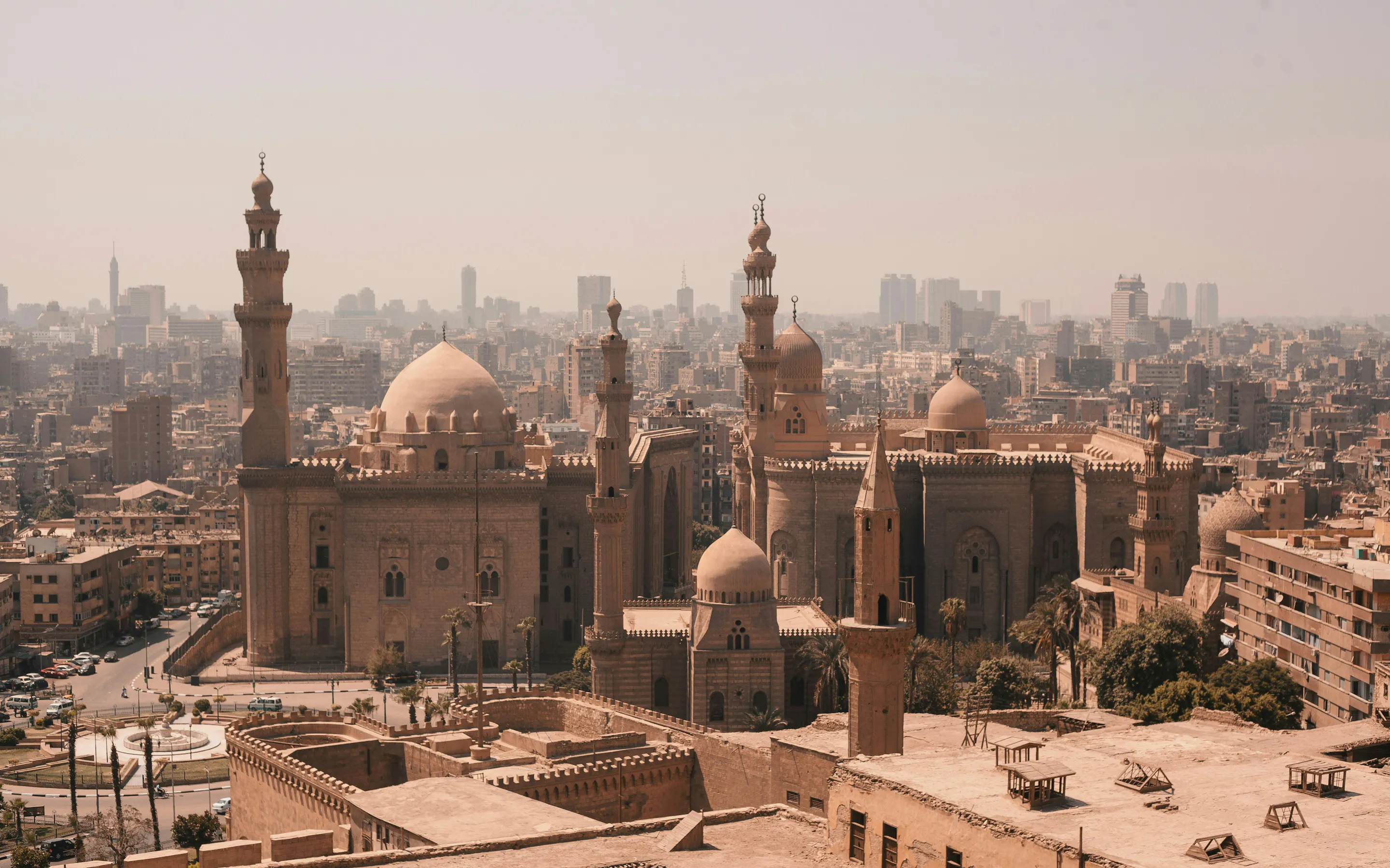 A panoramic view of Cairo's dense cityscape with mosques and minarets rising against a hazy sky.