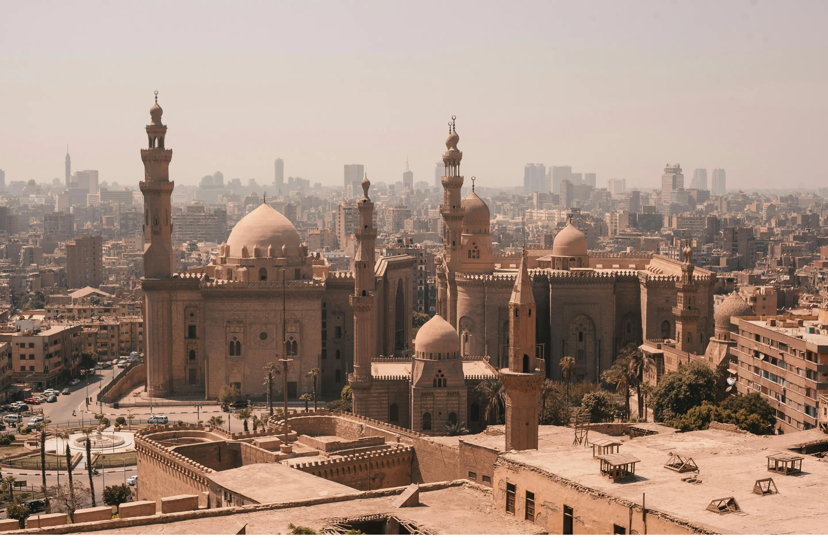 A panoramic view of Cairo's dense cityscape with mosques and minarets rising against a hazy sky.