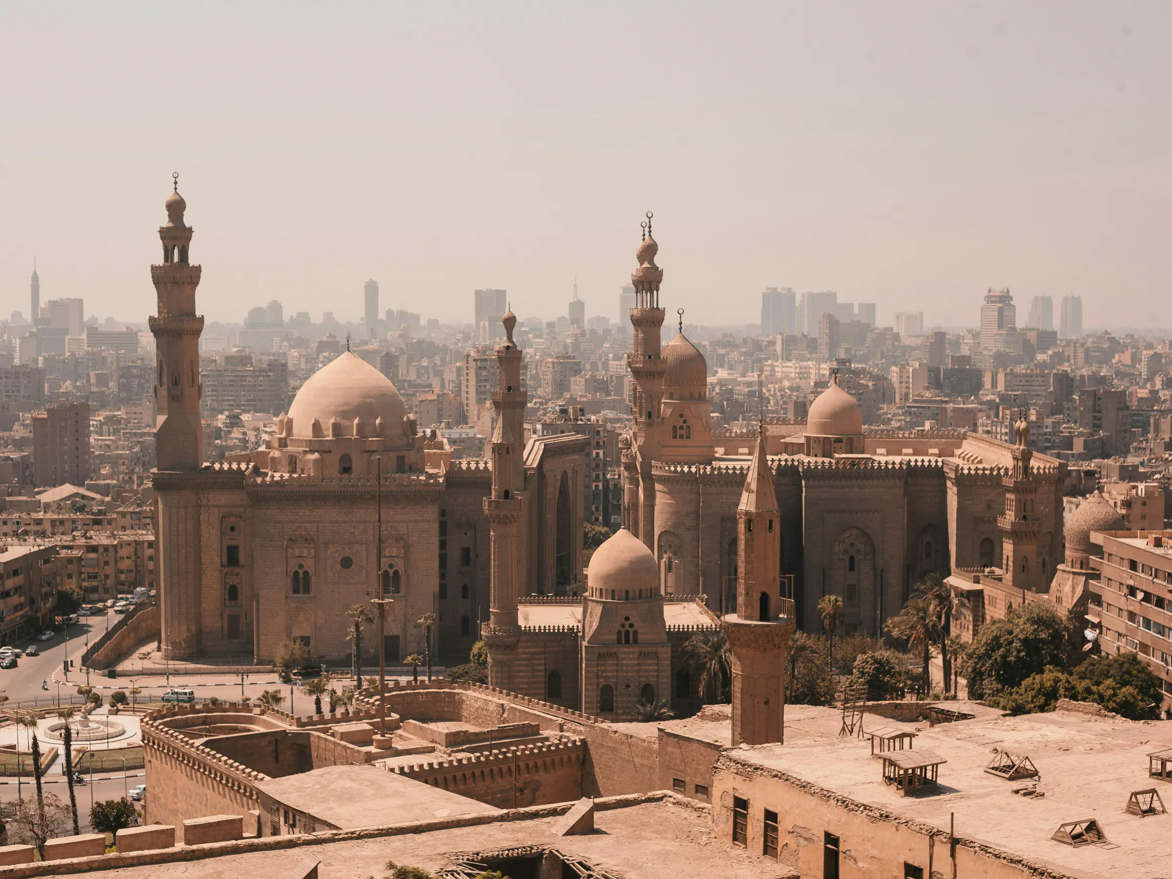 A panoramic view of Cairo's dense cityscape with mosques and minarets rising against a hazy sky.