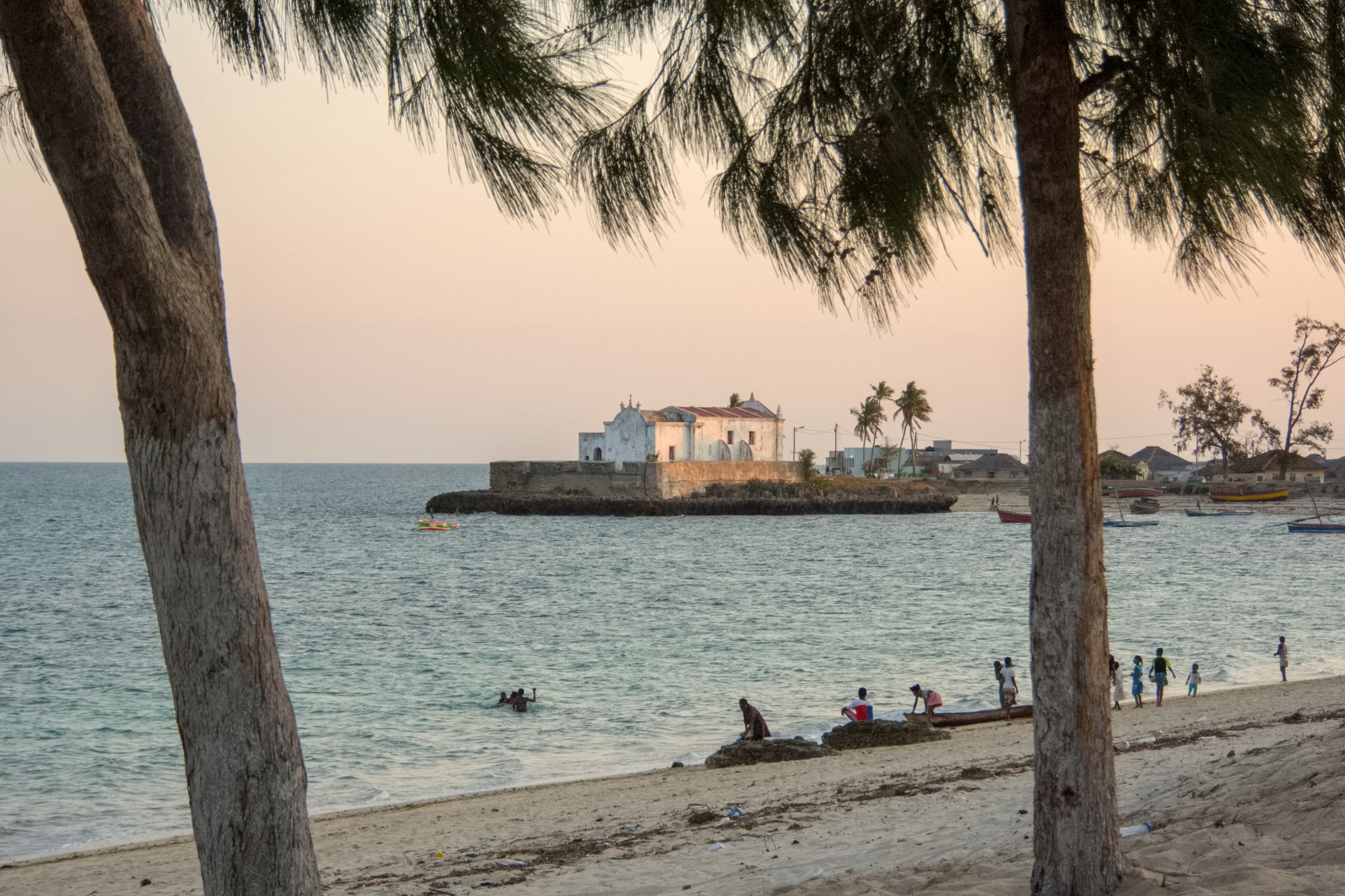 A narrow street on Ilha de Moçambique is lined with weathered colonial-era buildings.