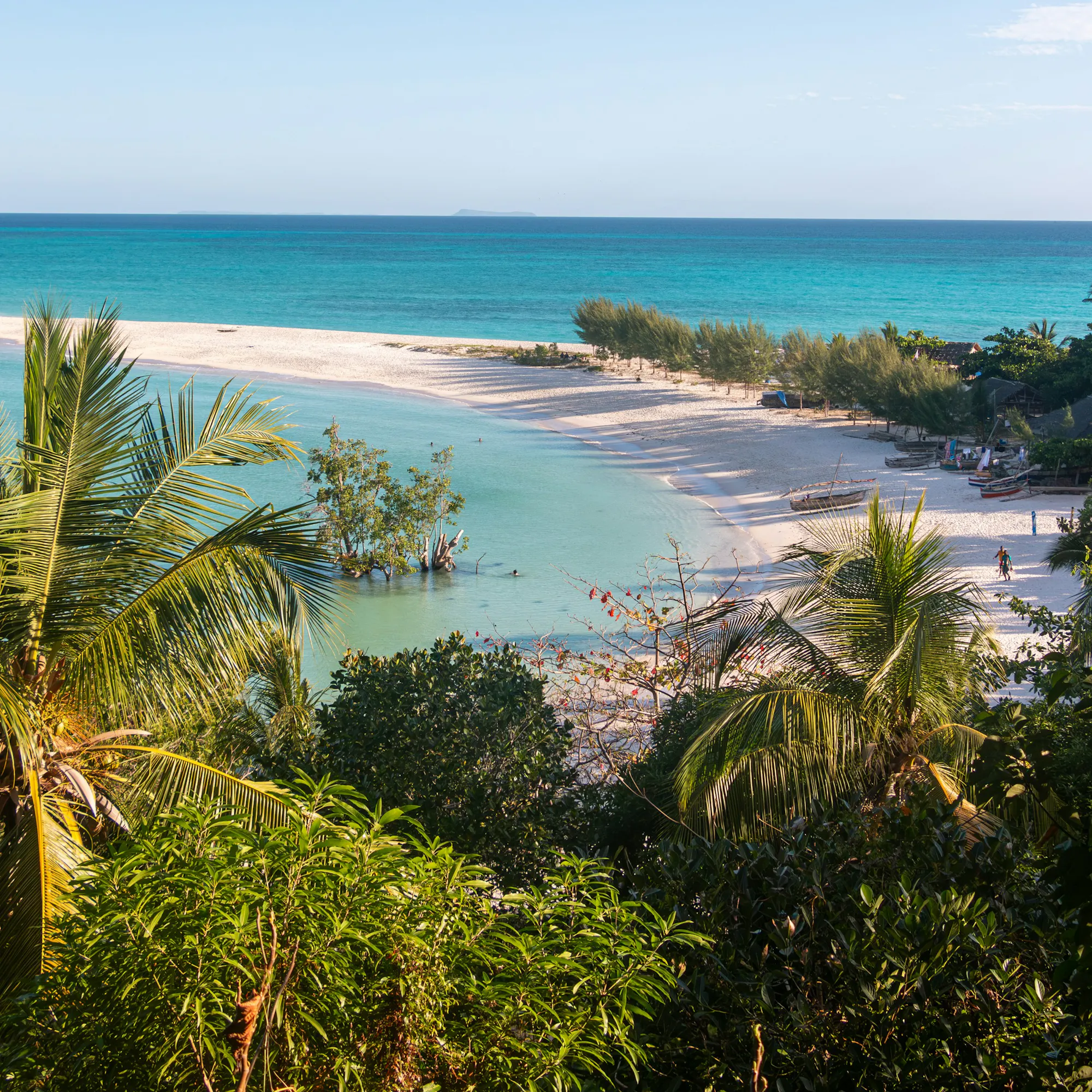 Turquoise water laps a pristine sandy beach framed by lush tropical vegetation in northern Madagascar.