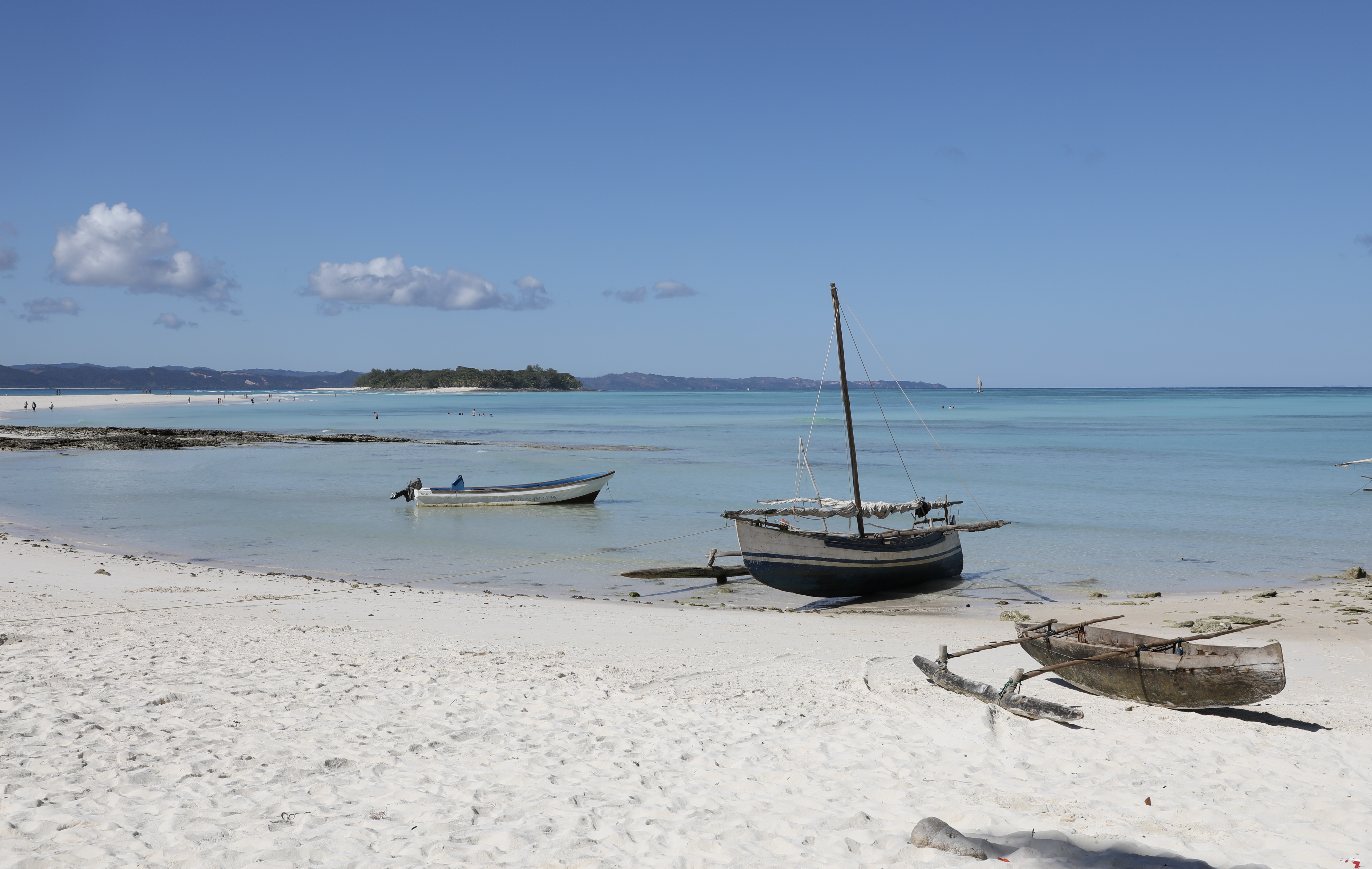 A traditional wooden outrigger canoe floats in calm turquoise water near Nosy Iranja, Mozambique.