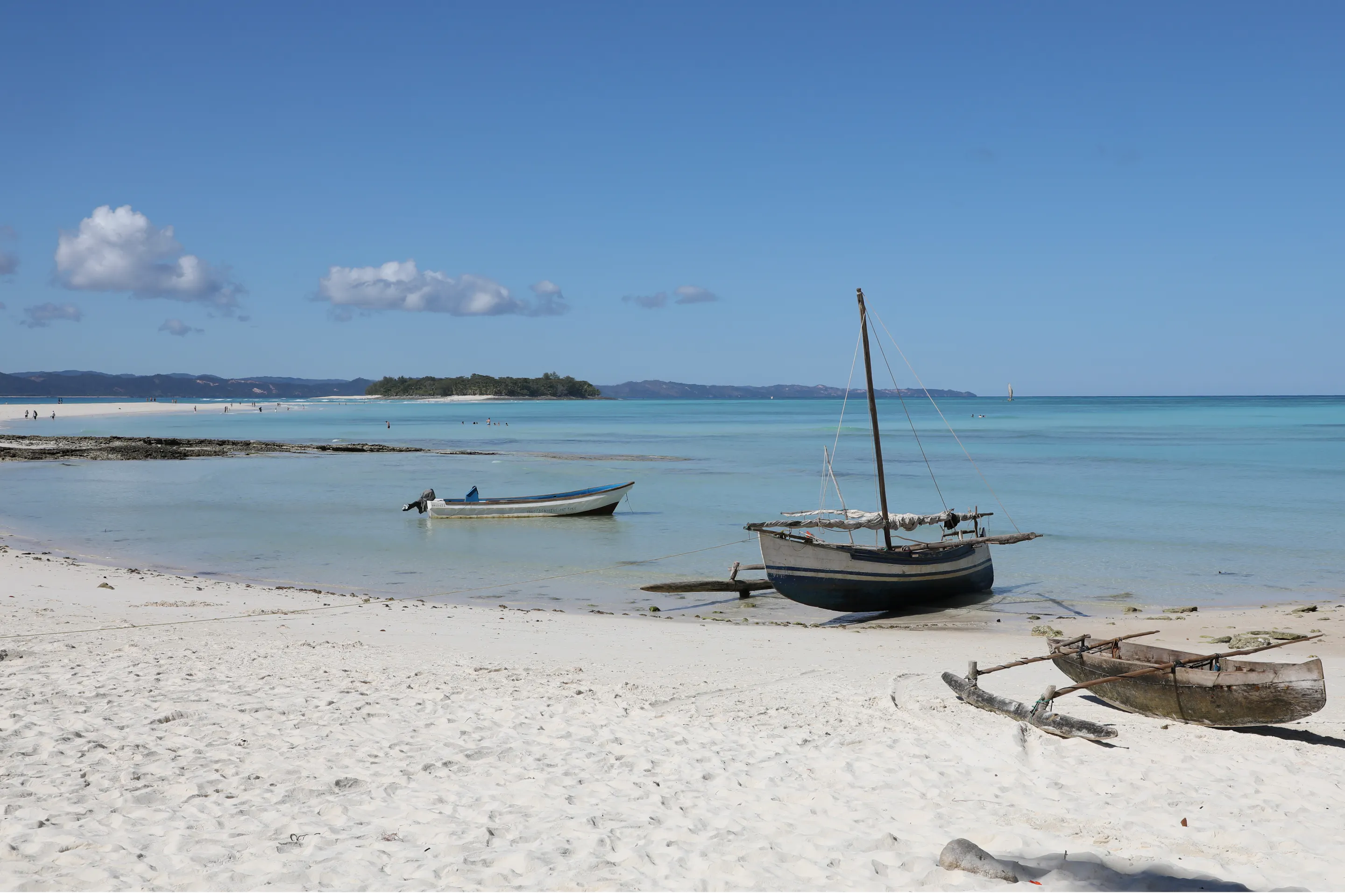 A traditional wooden outrigger canoe floats in calm turquoise water near Nosy Iranja, Mozambique.