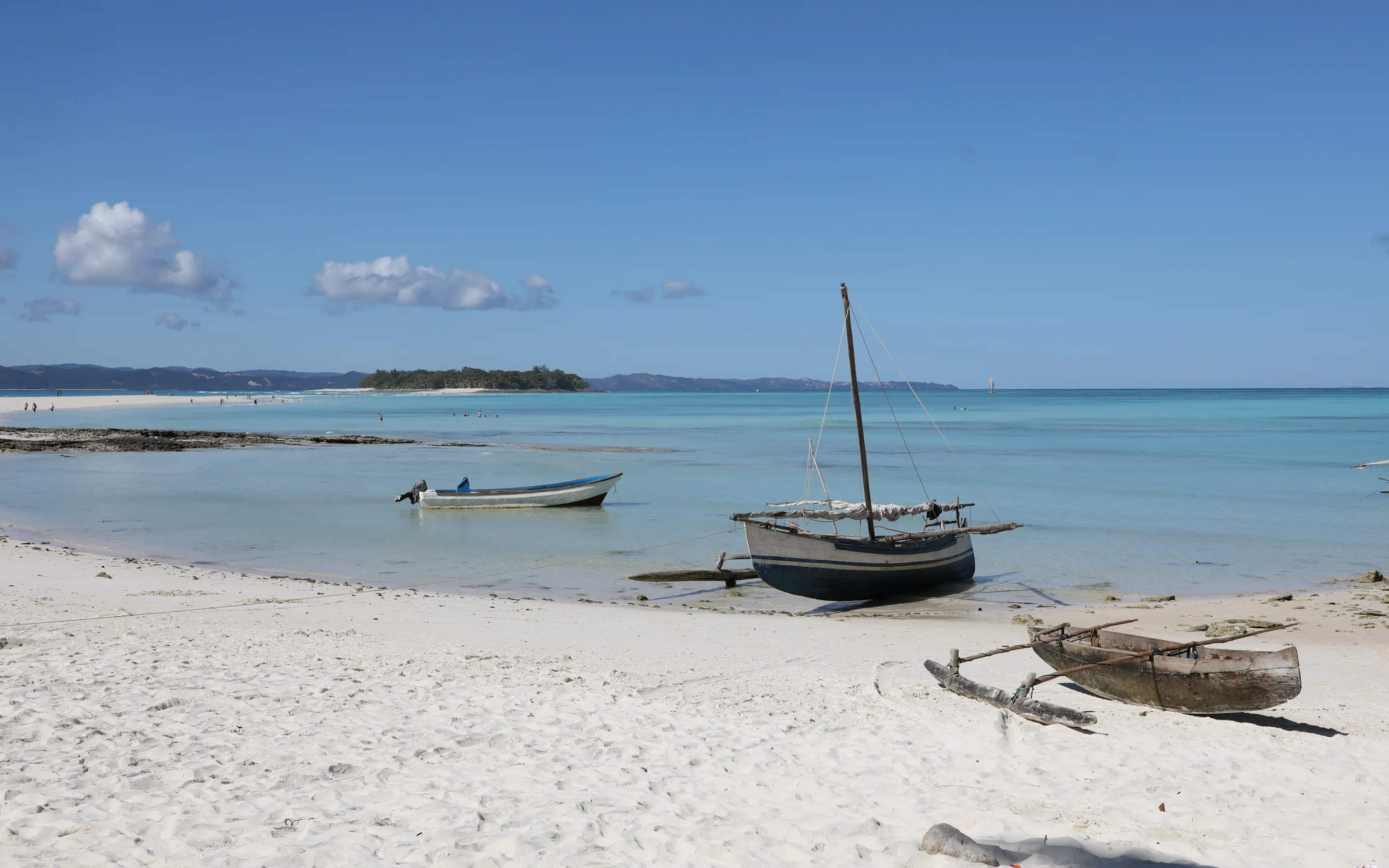 A traditional wooden outrigger canoe floats in calm turquoise water near Nosy Iranja, Mozambique.