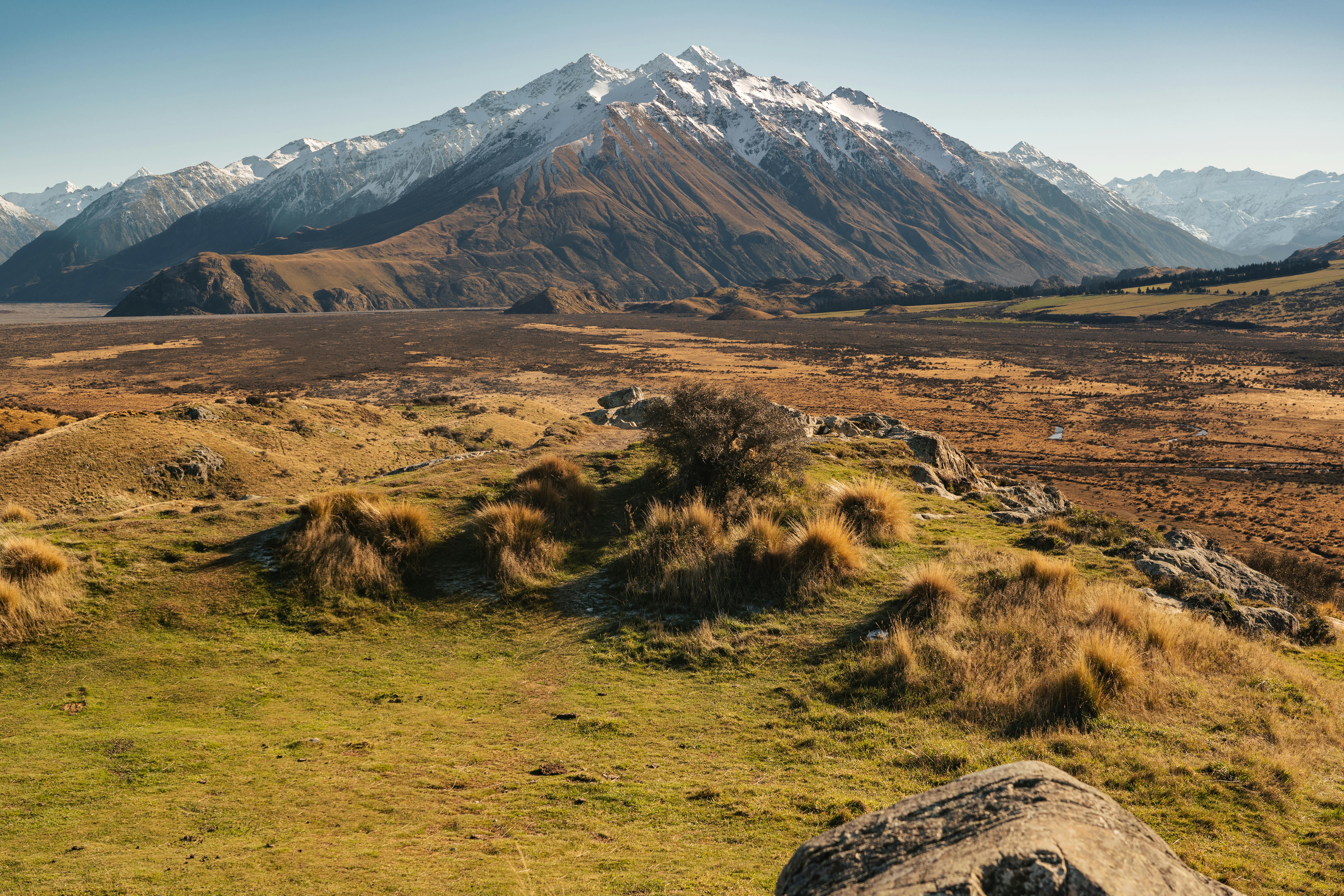 Green rolling hills and patchwork farmland sweep toward the coastline near Christchurch, New Zealand.