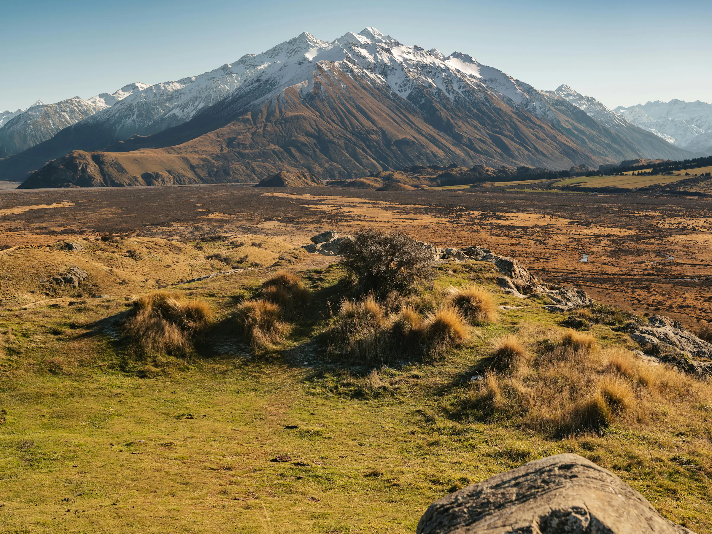 Green rolling hills and patchwork farmland sweep toward the coastline near Christchurch, New Zealand.