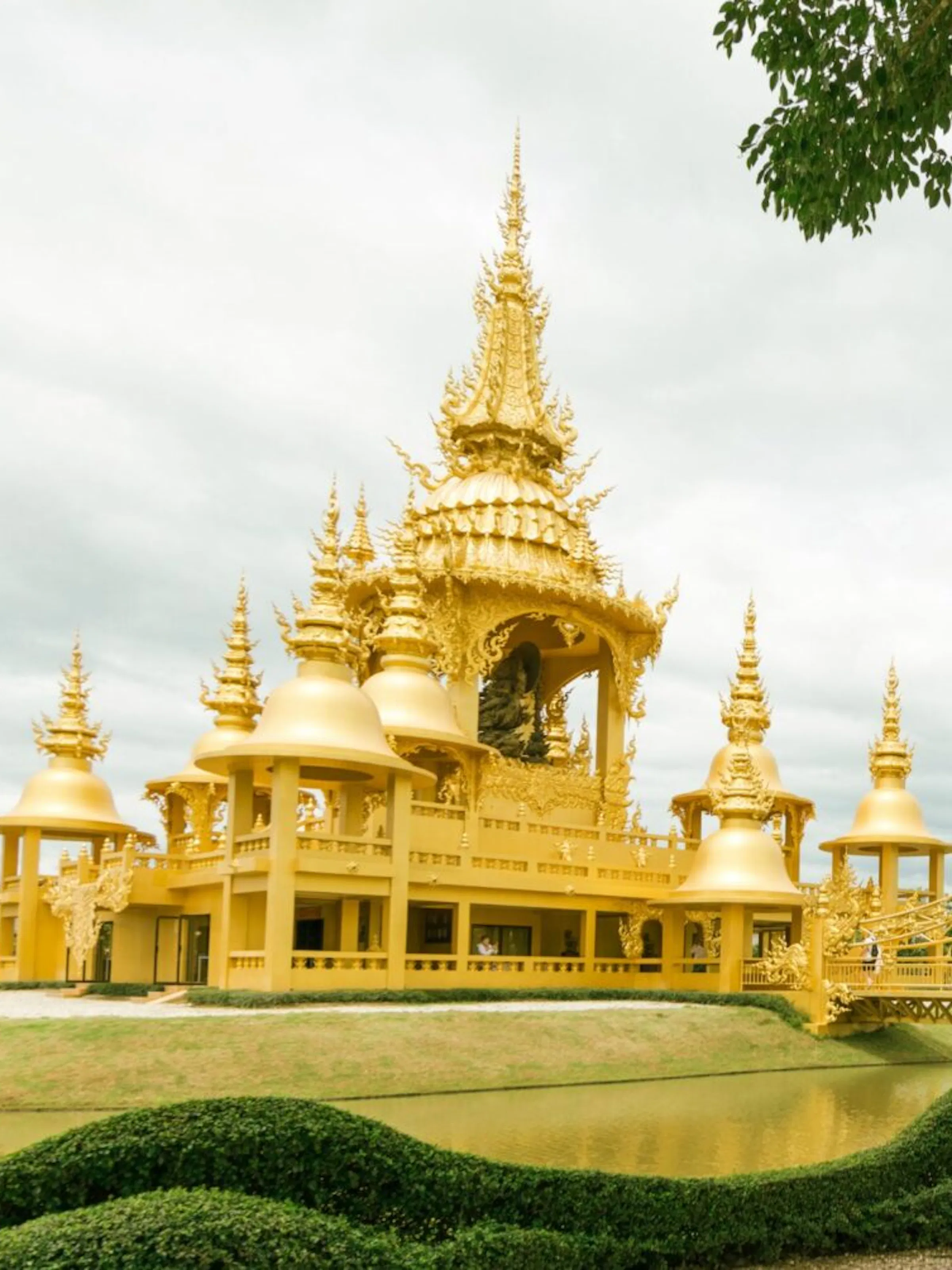 The gleaming white spires and ornate details of the White Temple in Chiang Rai under blue sky.