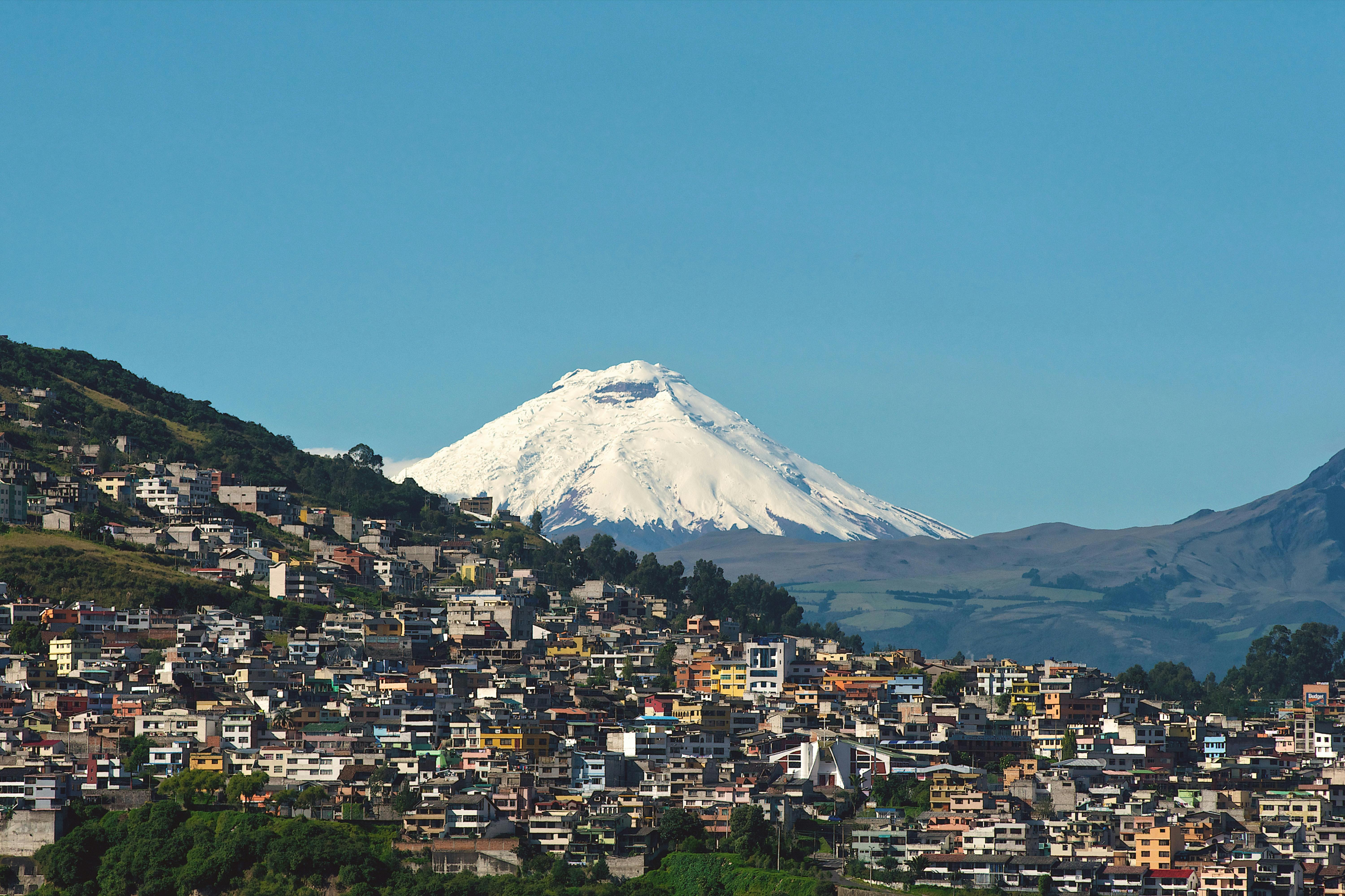 Quito's densely built cityscape fills a mountain valley with volcanic peaks visible on the horizon.
