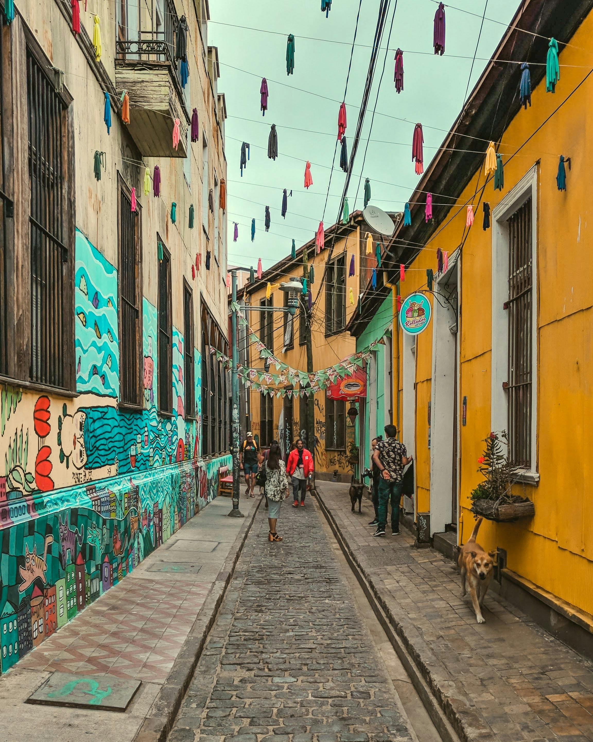 Brightly painted yellow and teal building facades line a steep narrow street in Valparaíso.