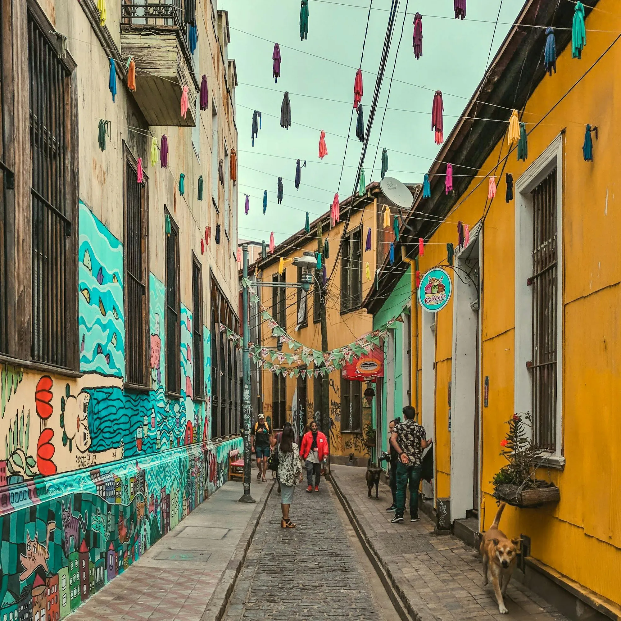 Brightly painted yellow and teal building facades line a steep narrow street in Valparaíso.