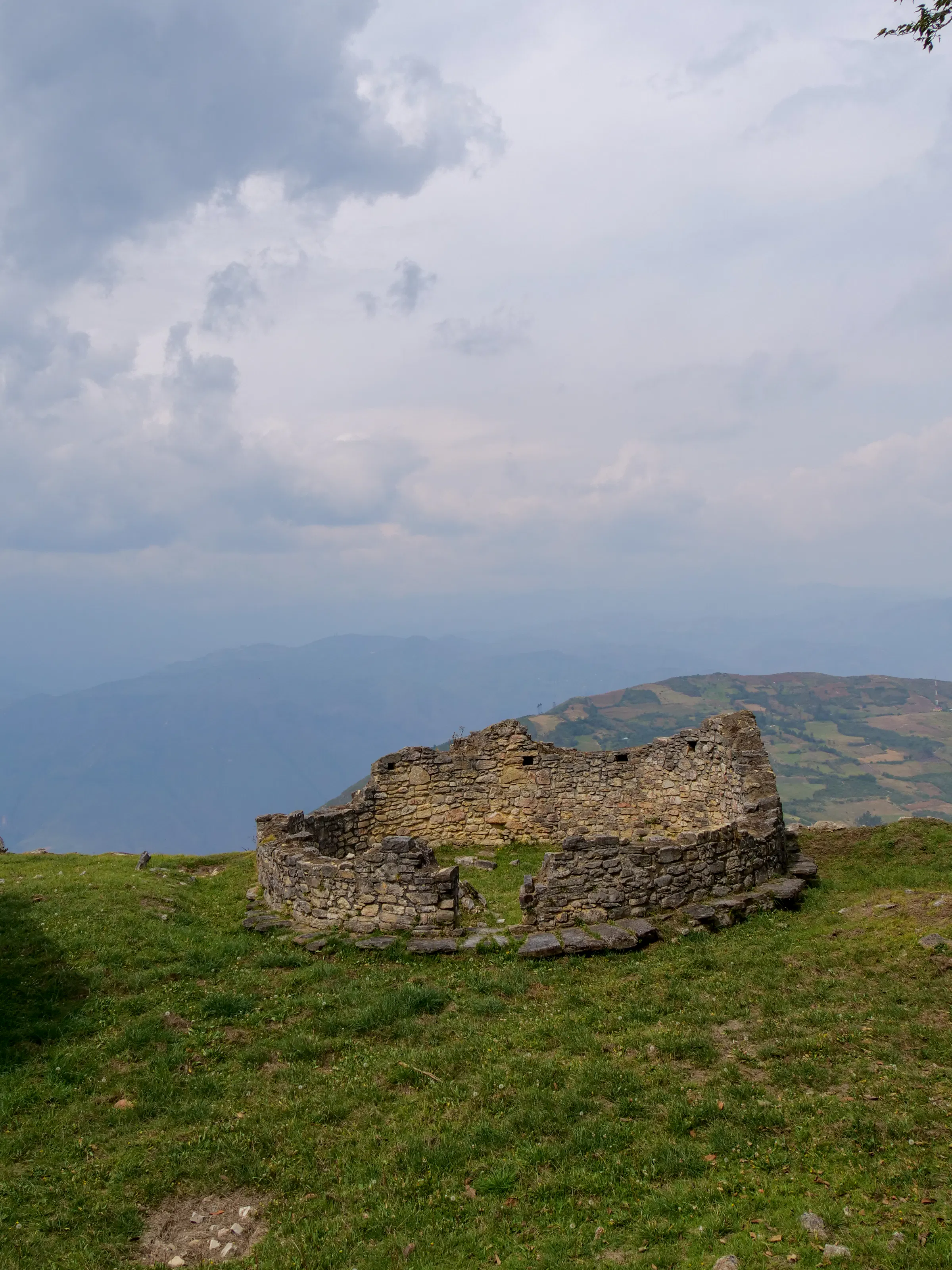 Ancient stone walls and circular dwellings of the Kuelap fortress rise among mist and greenery.