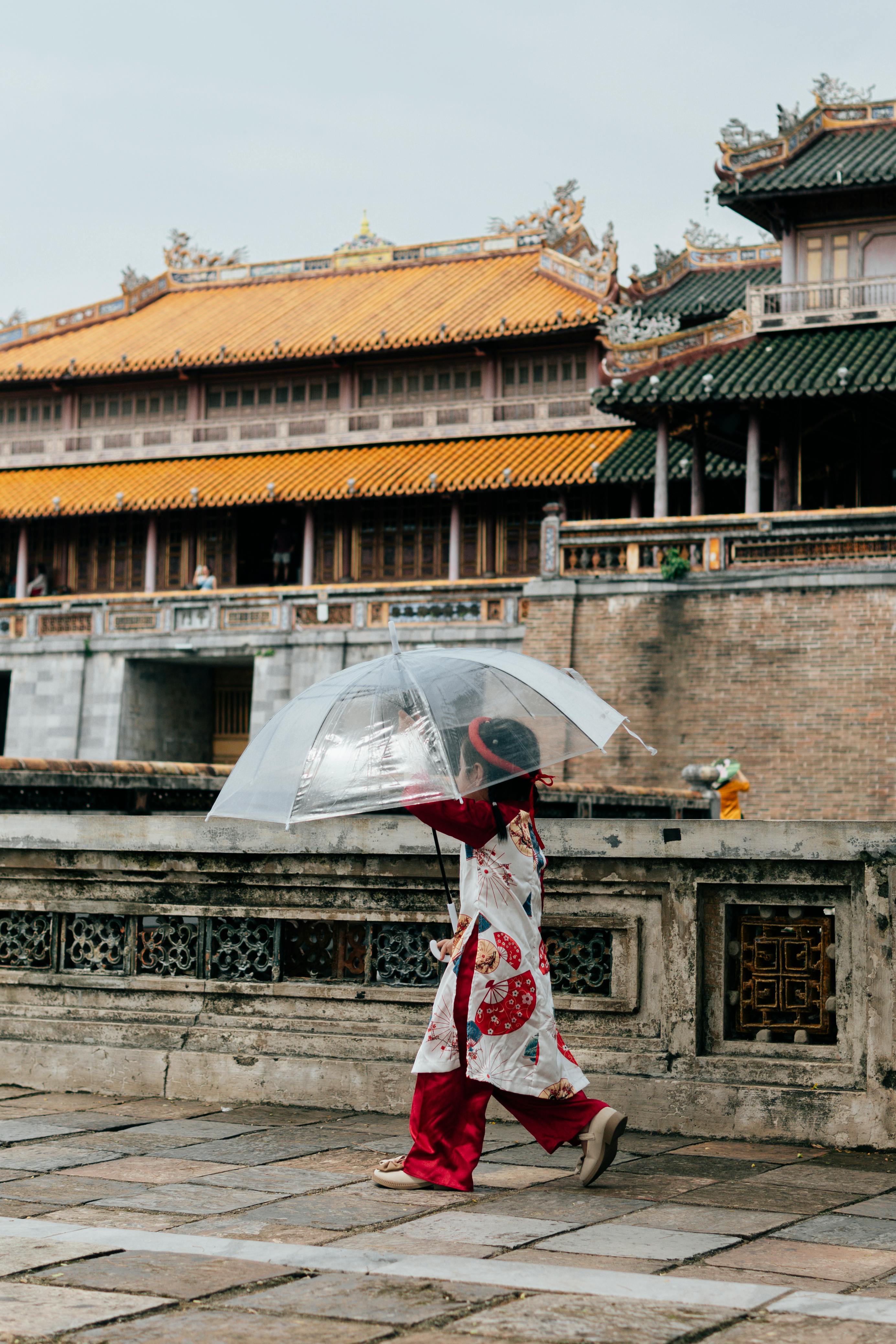 A woman in traditional ao dai walks past ornate yellow walls at the Imperial Citadel in Hue.