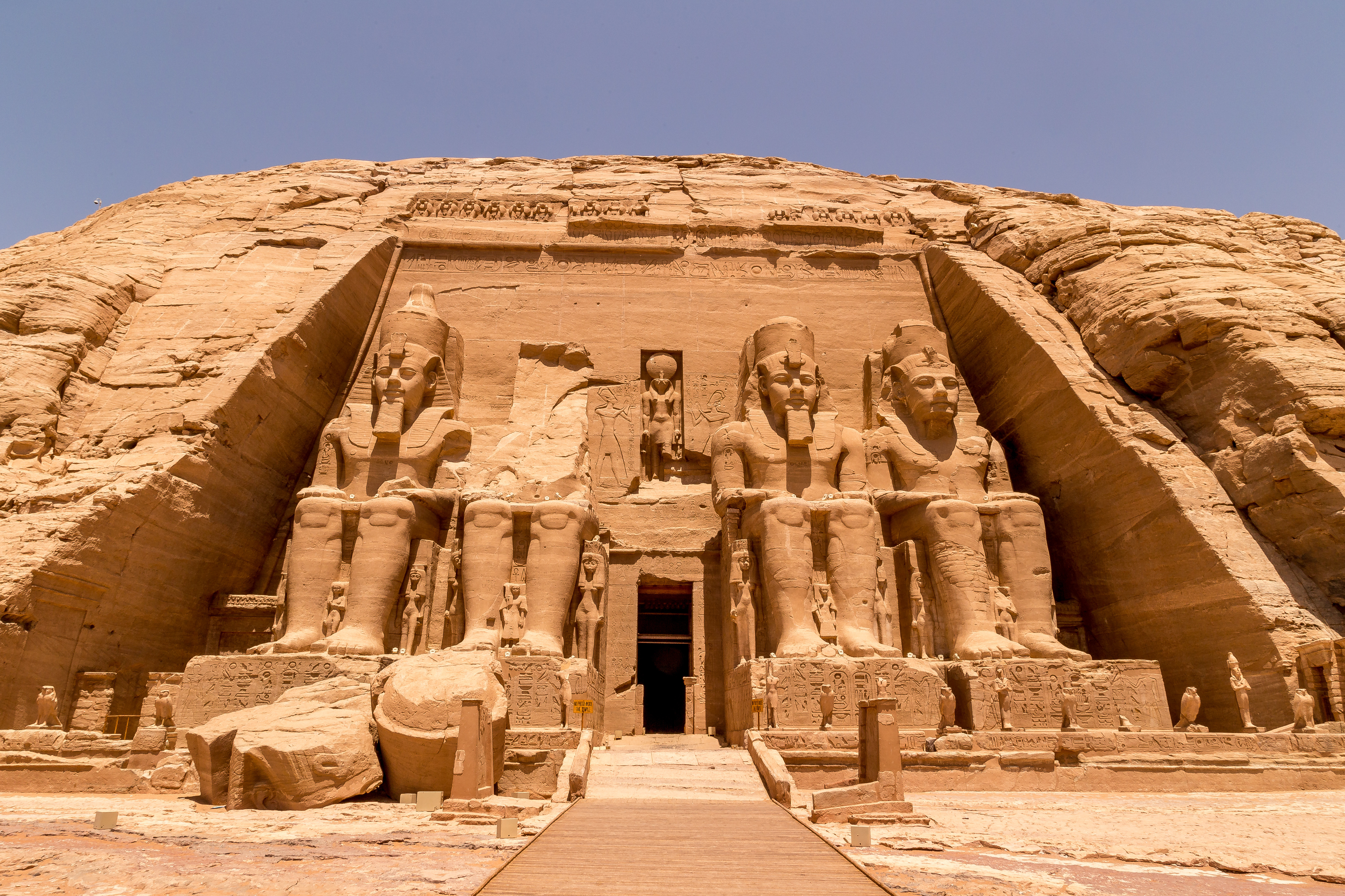 The massive carved facade of Abu Simbel temple features four colossal seated pharaoh statues.