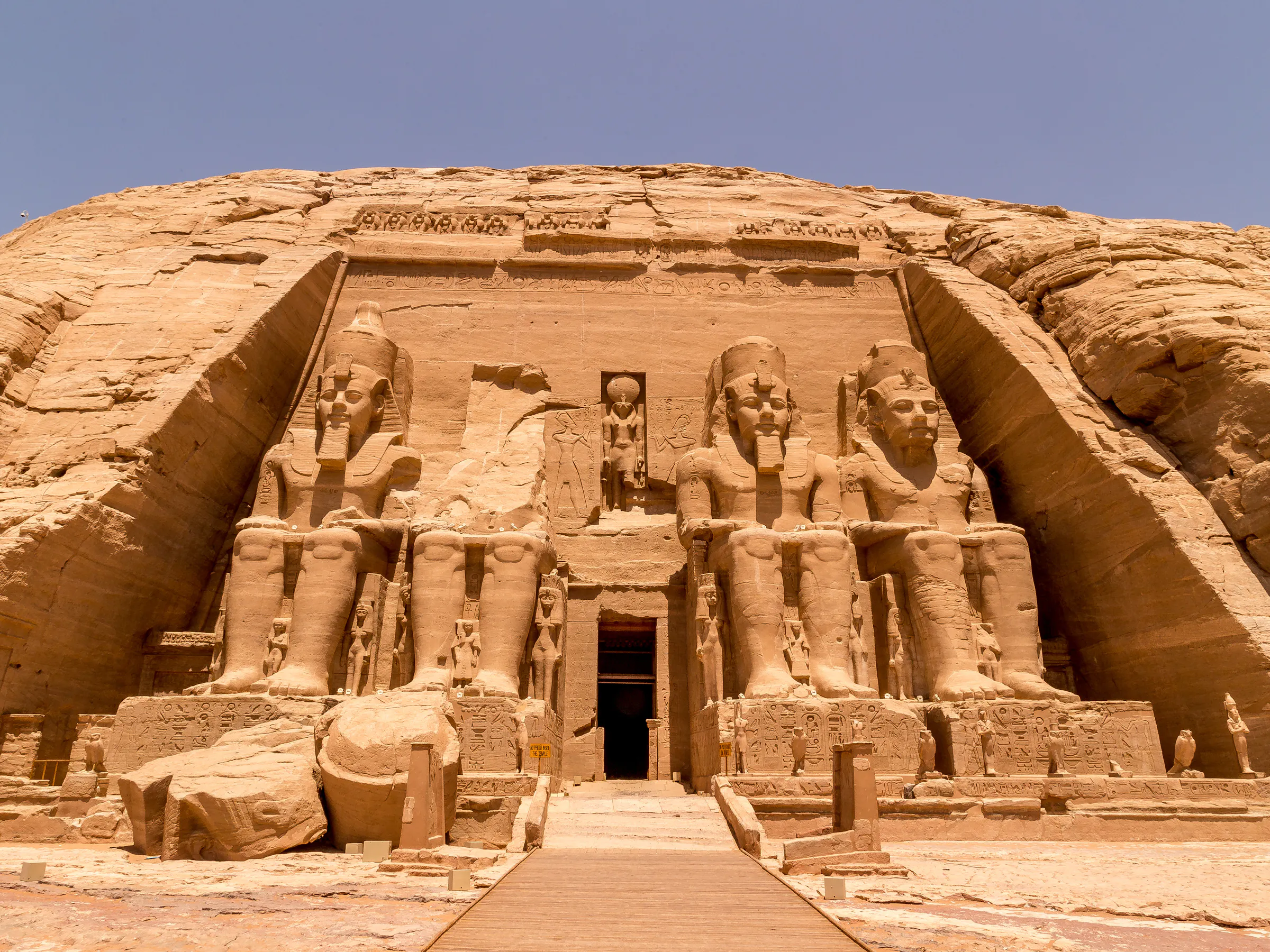 The massive carved facade of Abu Simbel temple features four colossal seated pharaoh statues.