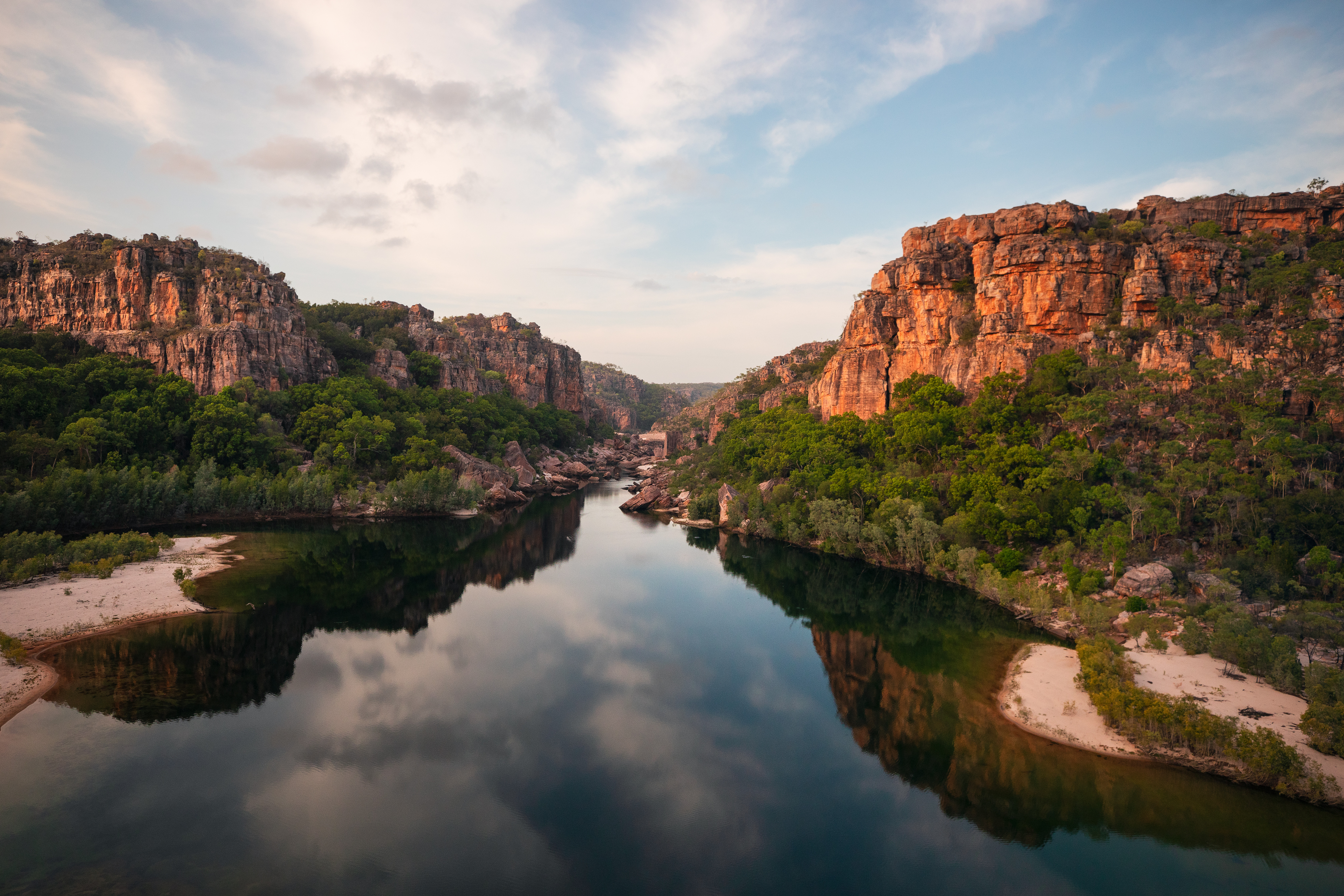 A river winds through a broad rocky gorge with red sandstone walls in Kakadu National Park.