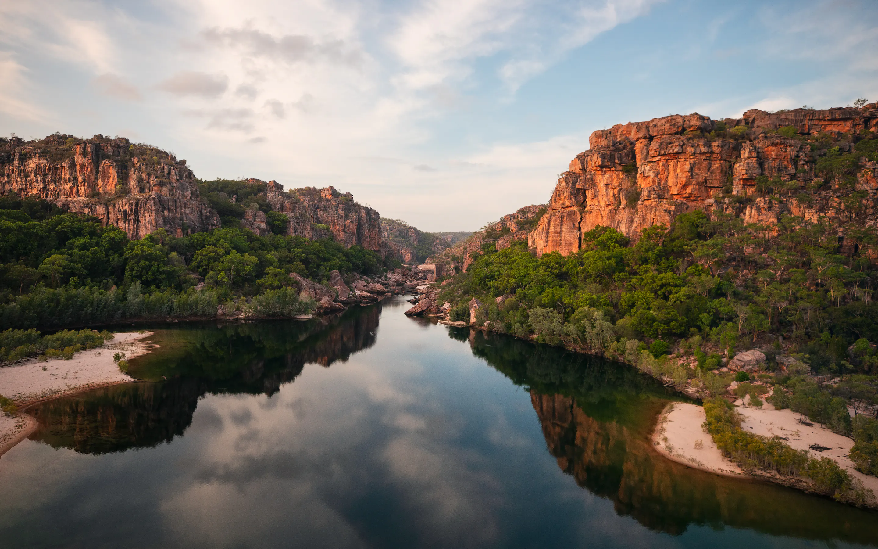 A river winds through a broad rocky gorge with red sandstone walls in Kakadu National Park.