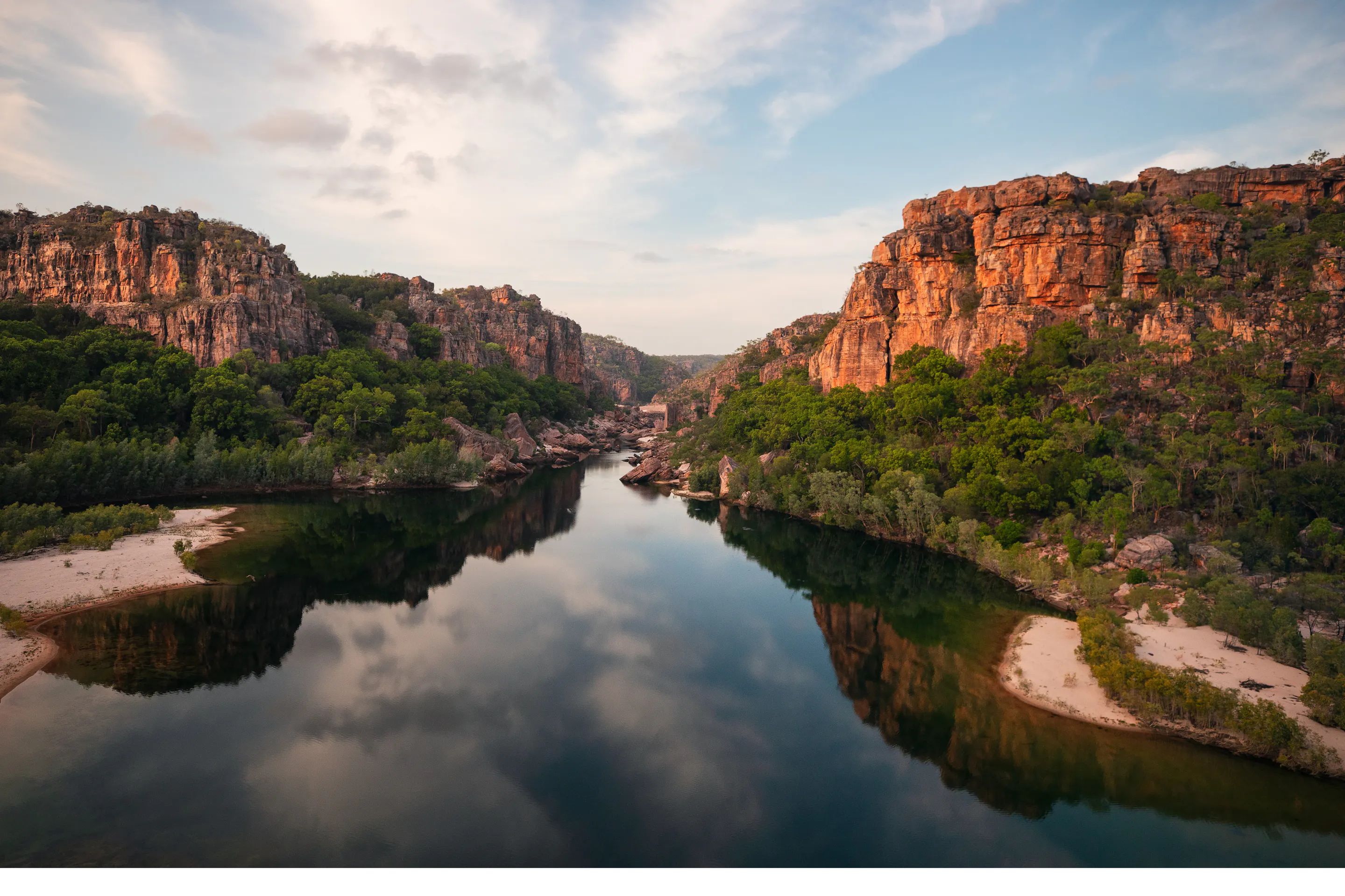 A river winds through a broad rocky gorge with red sandstone walls in Kakadu National Park.