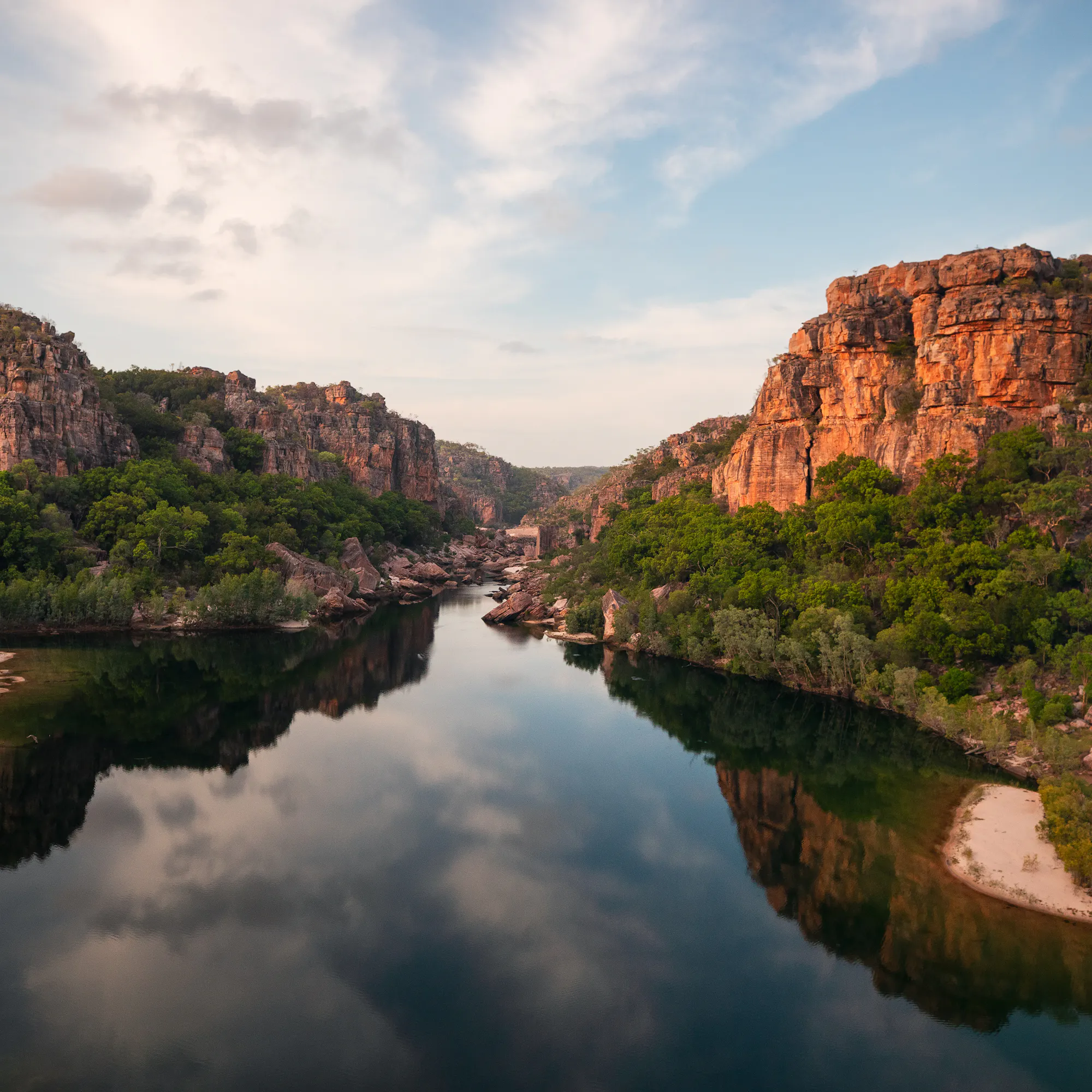 A river winds through a broad rocky gorge with red sandstone walls in Kakadu National Park.