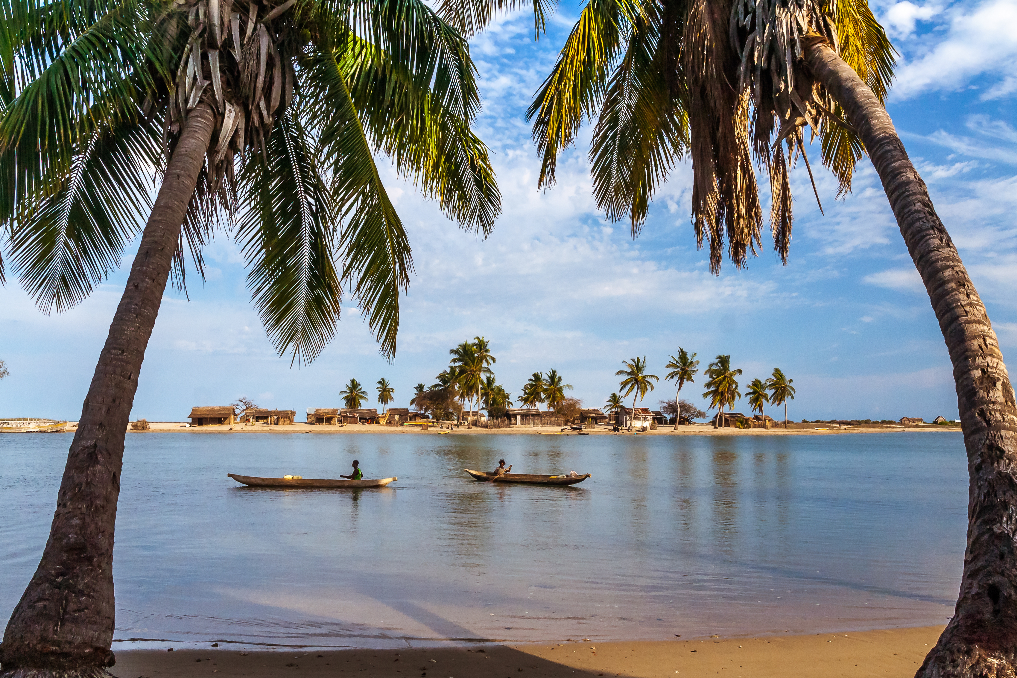 Malagasy villagers row traditional dugout canoes across a calm lagoon near Belo sur Mer.