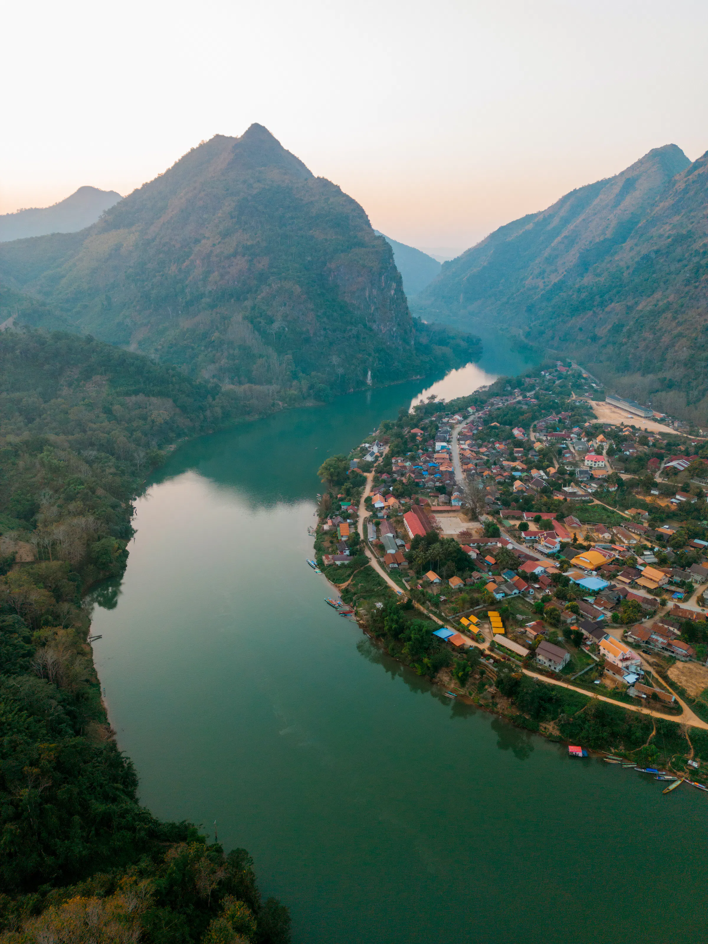 Aerial view of the Mekong River winding between green islands and flat delta land at sunset.