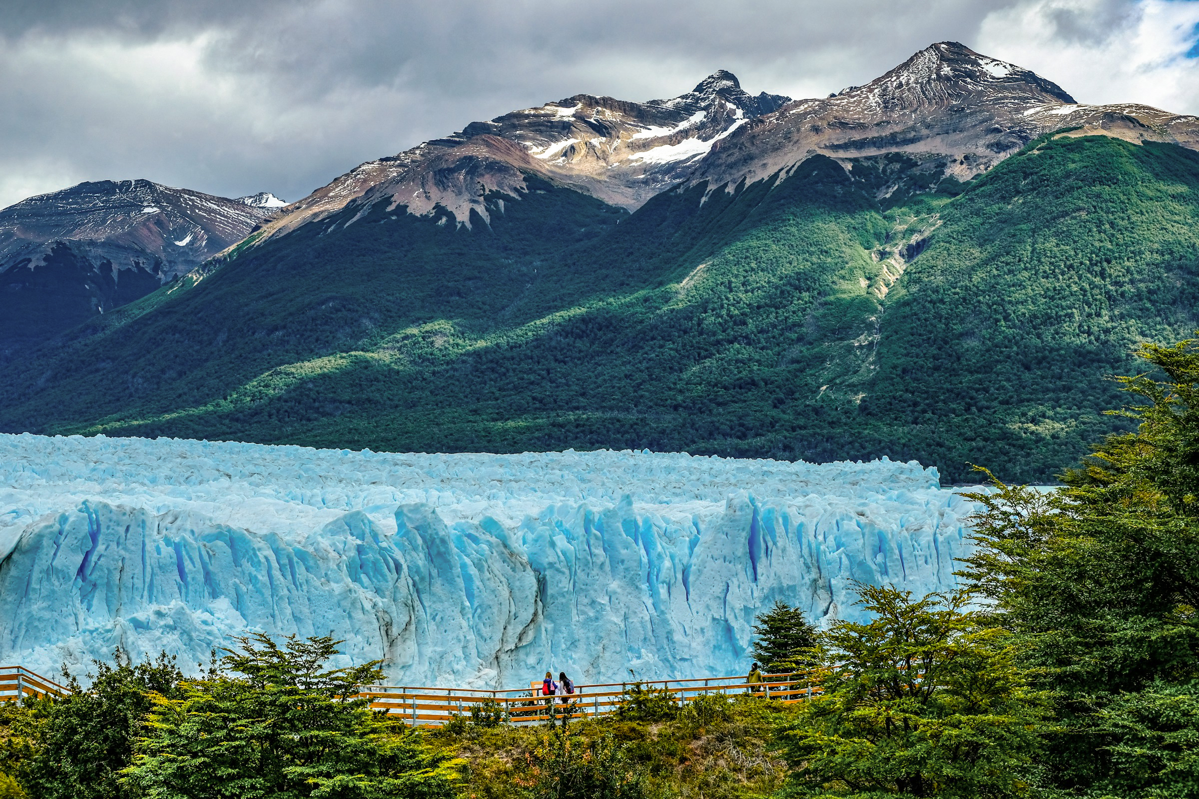 The deep blue ice face of Perito Moreno Glacier stretches wide with Andean peaks rising behind.
