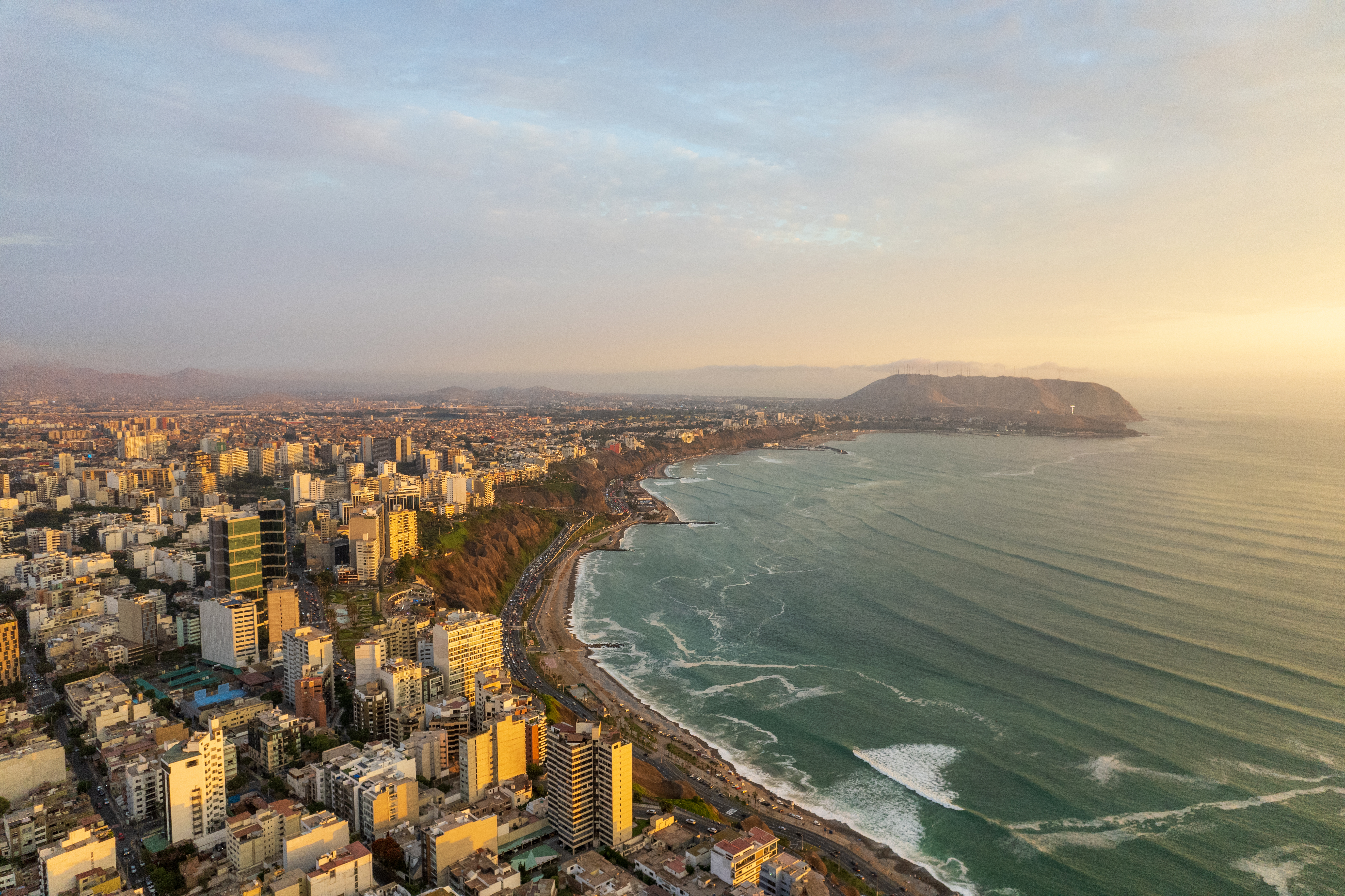 Aerial view of Lima's dense coastal cityscape stretching along cliffs above the Pacific Ocean.