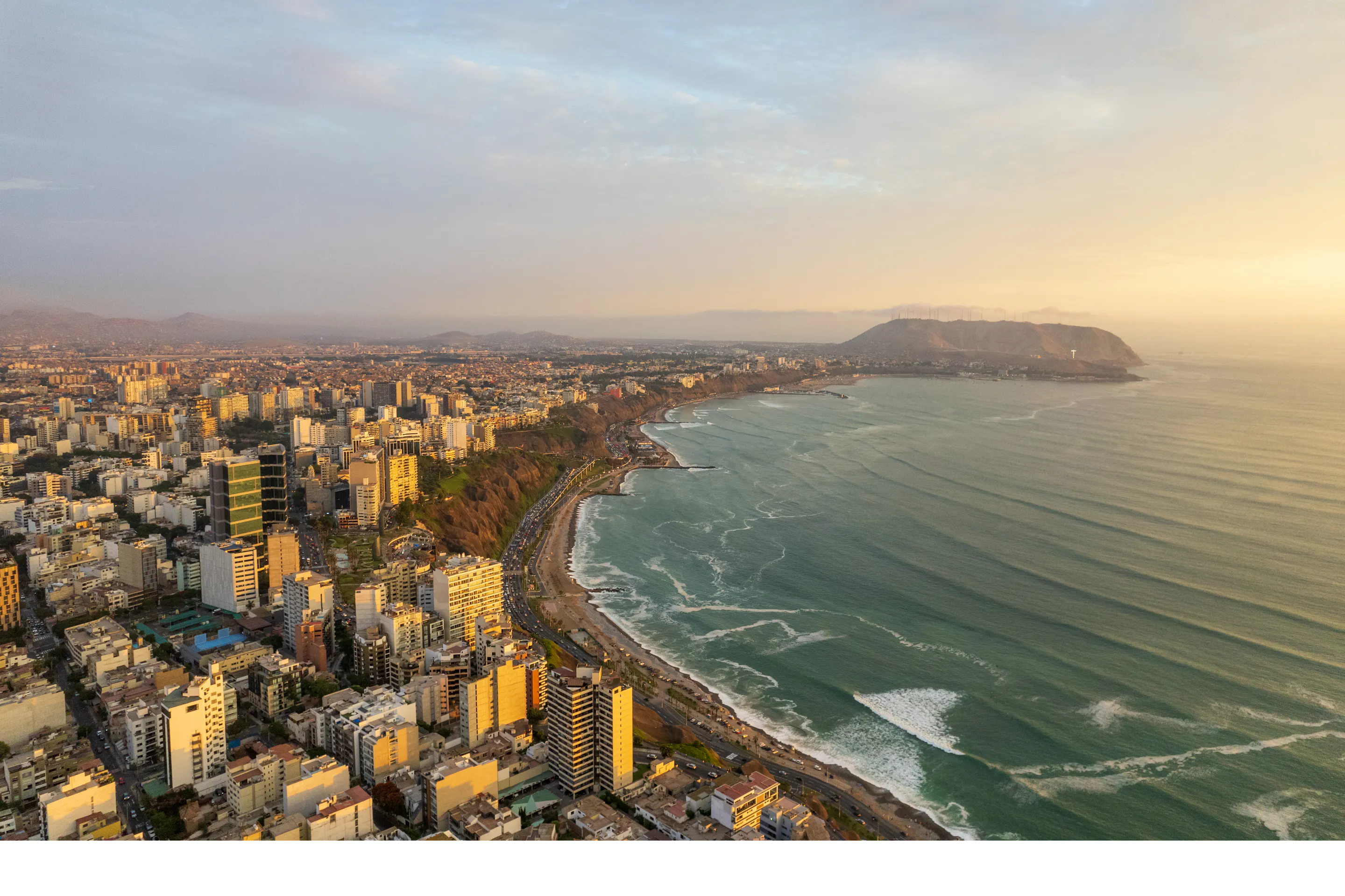 Aerial view of Lima's dense coastal cityscape stretching along cliffs above the Pacific Ocean.