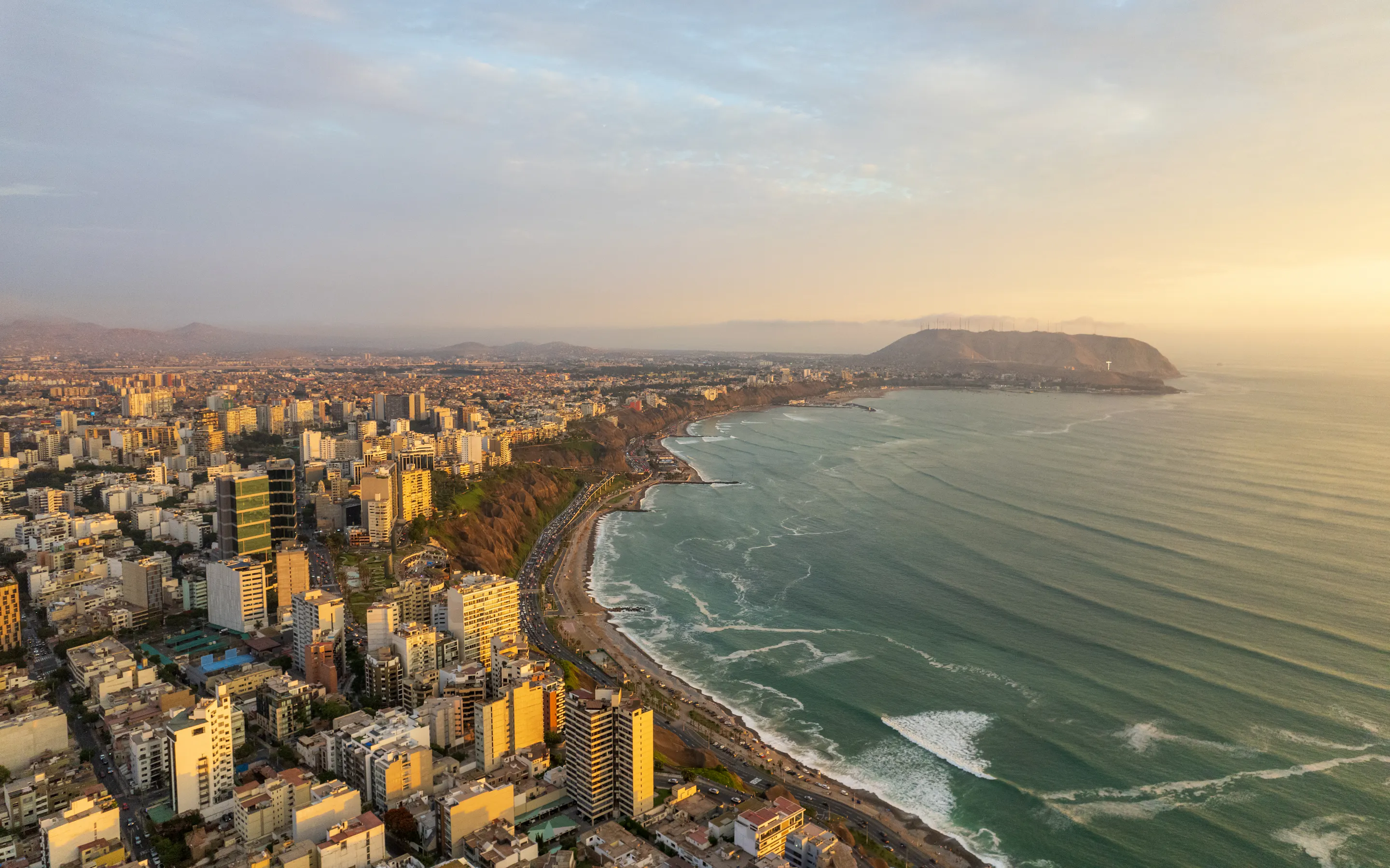 Aerial view of Lima's dense coastal cityscape stretching along cliffs above the Pacific Ocean.