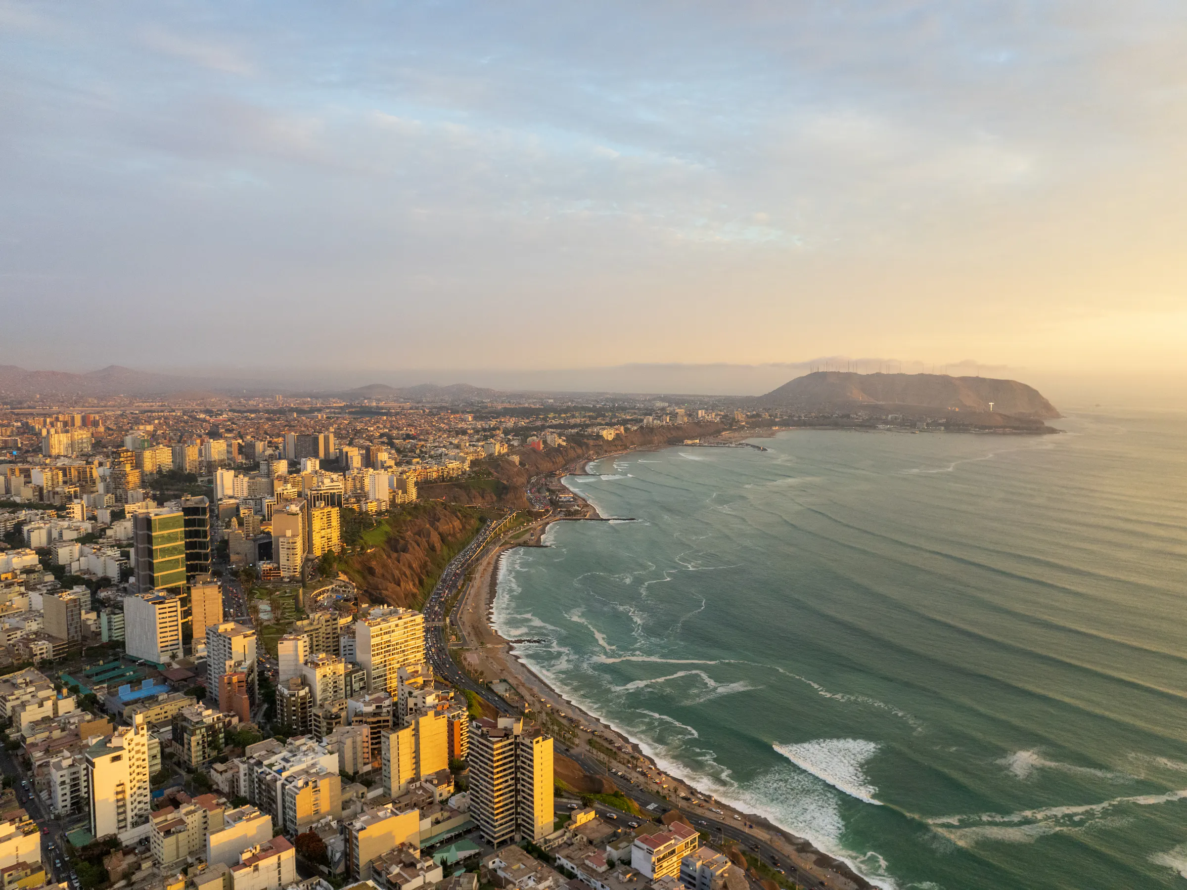 Aerial view of Lima's dense coastal cityscape stretching along cliffs above the Pacific Ocean.