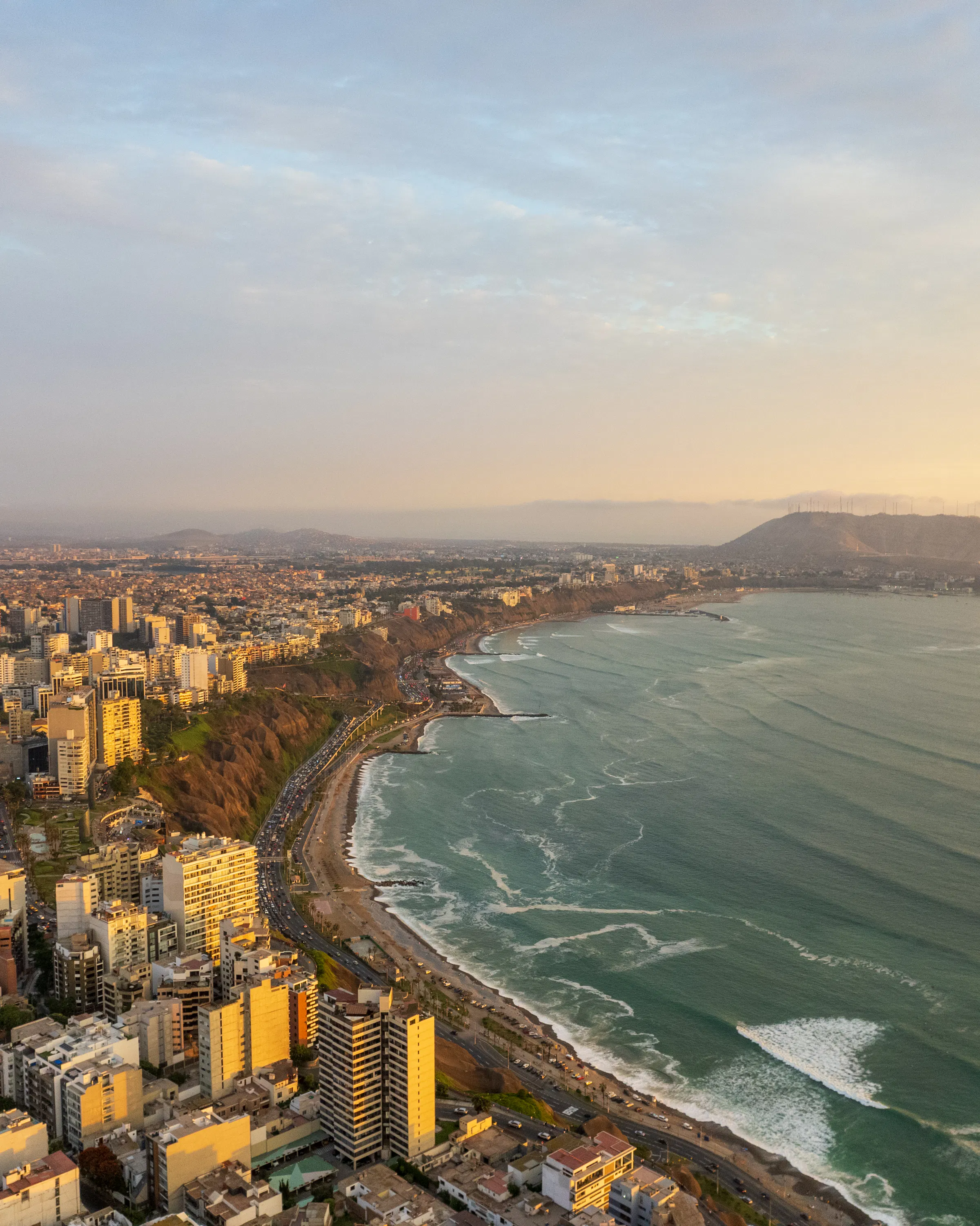 Aerial view of Lima's dense coastal cityscape stretching along cliffs above the Pacific Ocean.