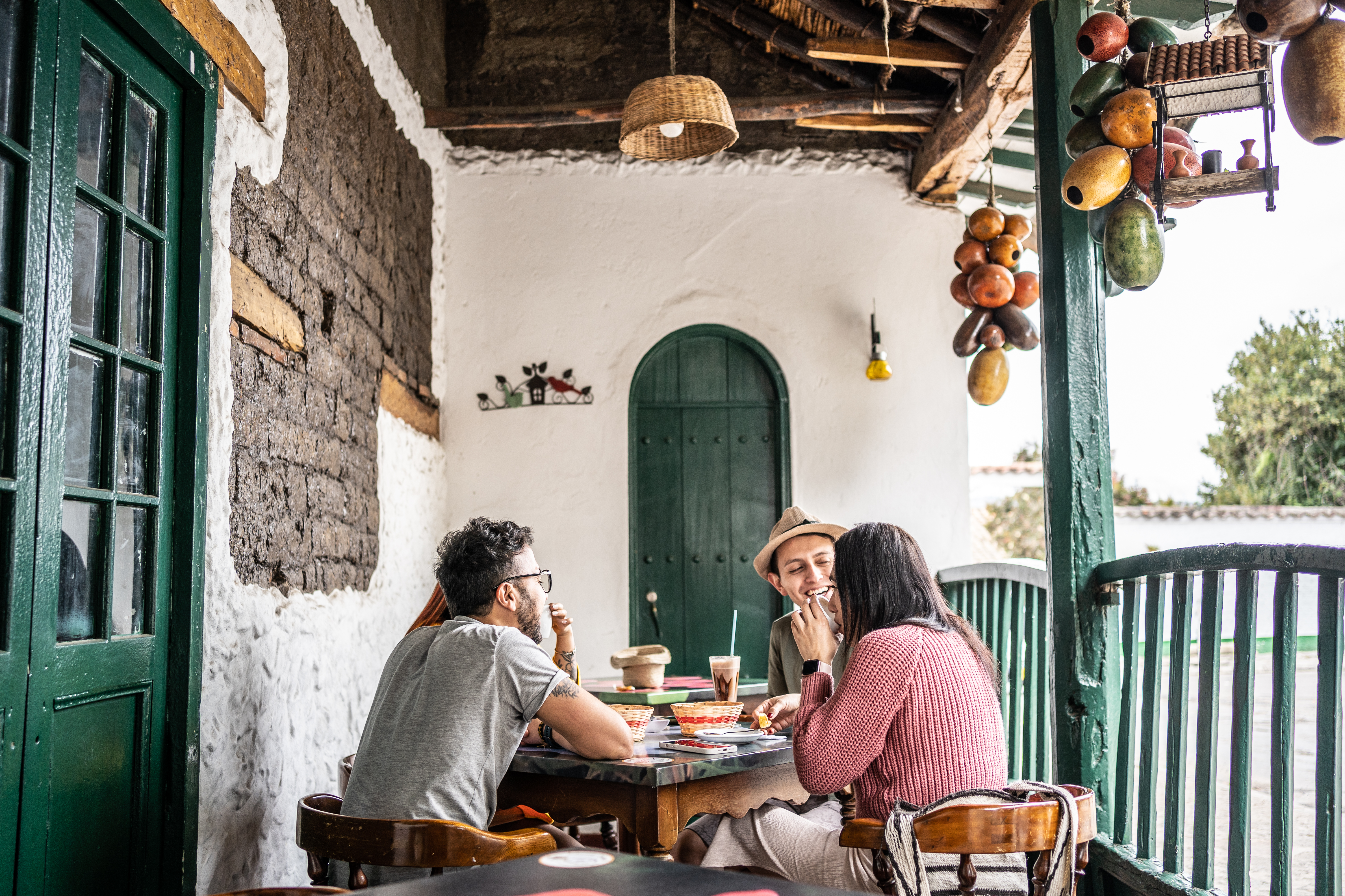 Two people share a meal on a shaded balcony overlooking a colonial courtyard in Villa de Leyva.
