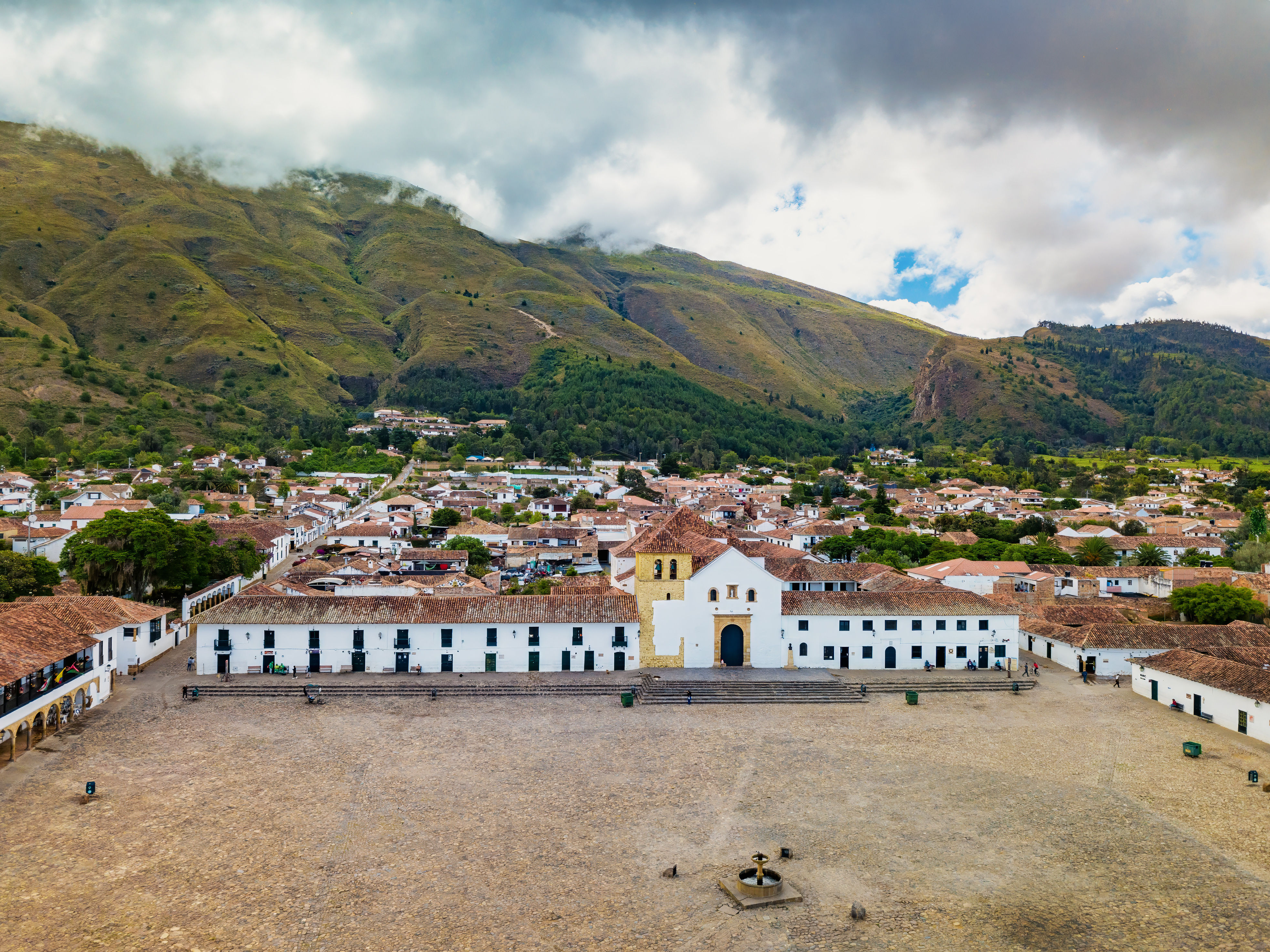The vast cobblestone plaza of Villa de Leyva is surrounded by white colonial buildings and mountains.