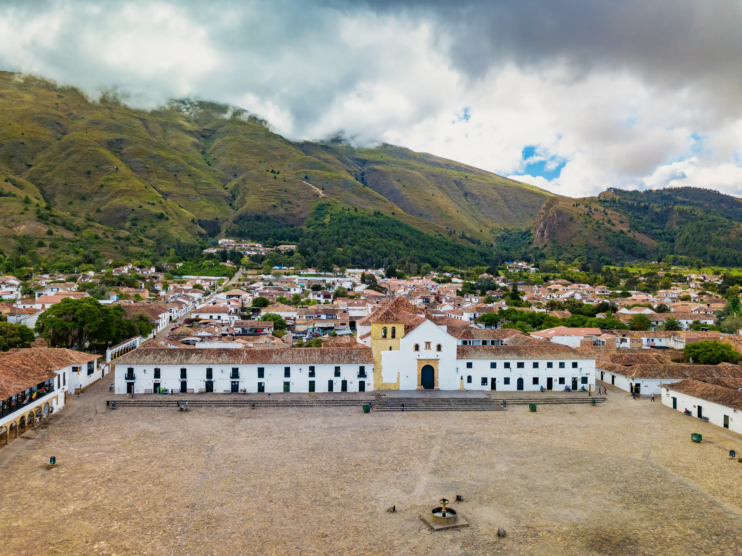 The vast cobblestone plaza of Villa de Leyva is surrounded by white colonial buildings and mountains.
