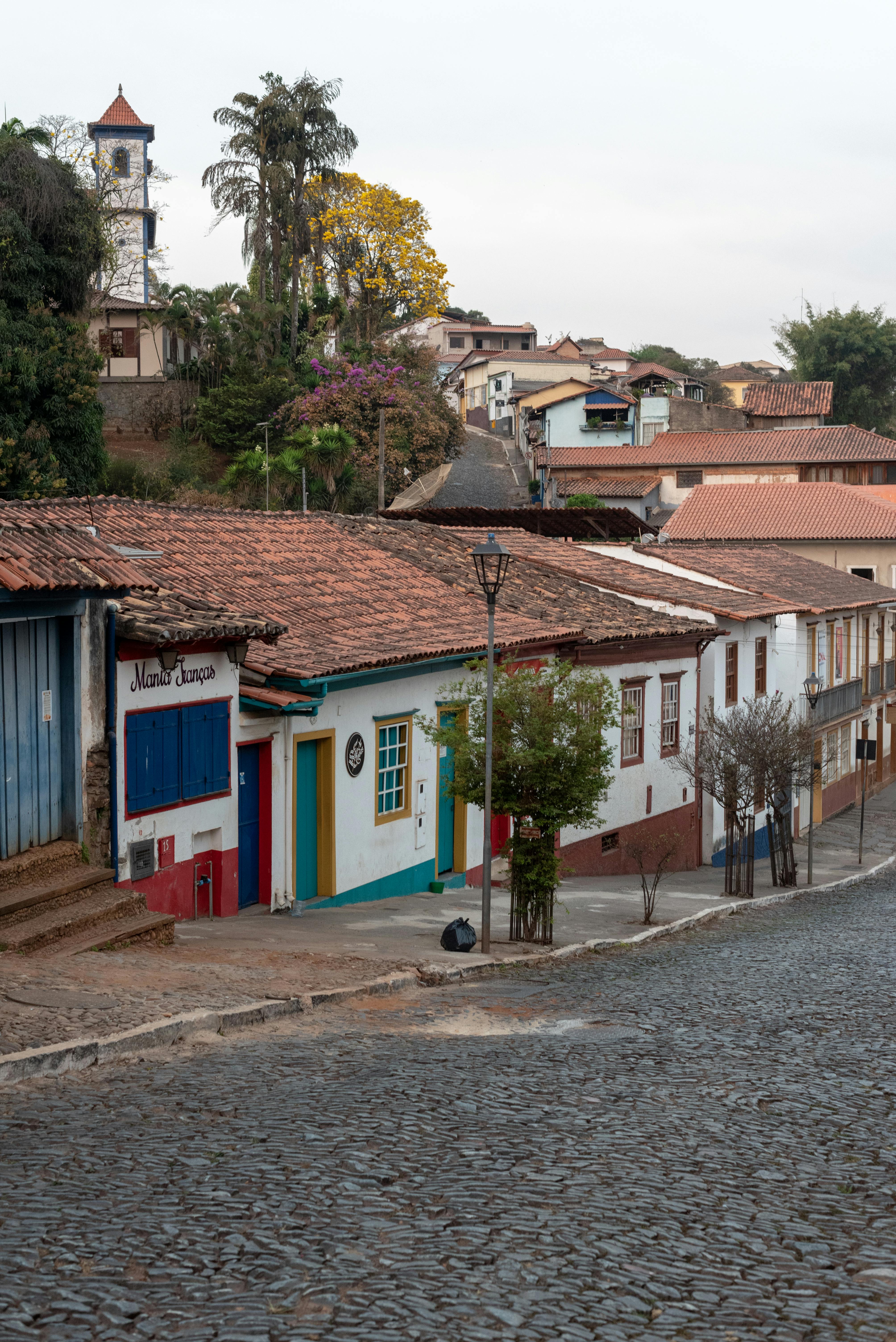 Rolling green hills and a valley town nestle beneath overcast skies in Minas Gerais, Brazil.
