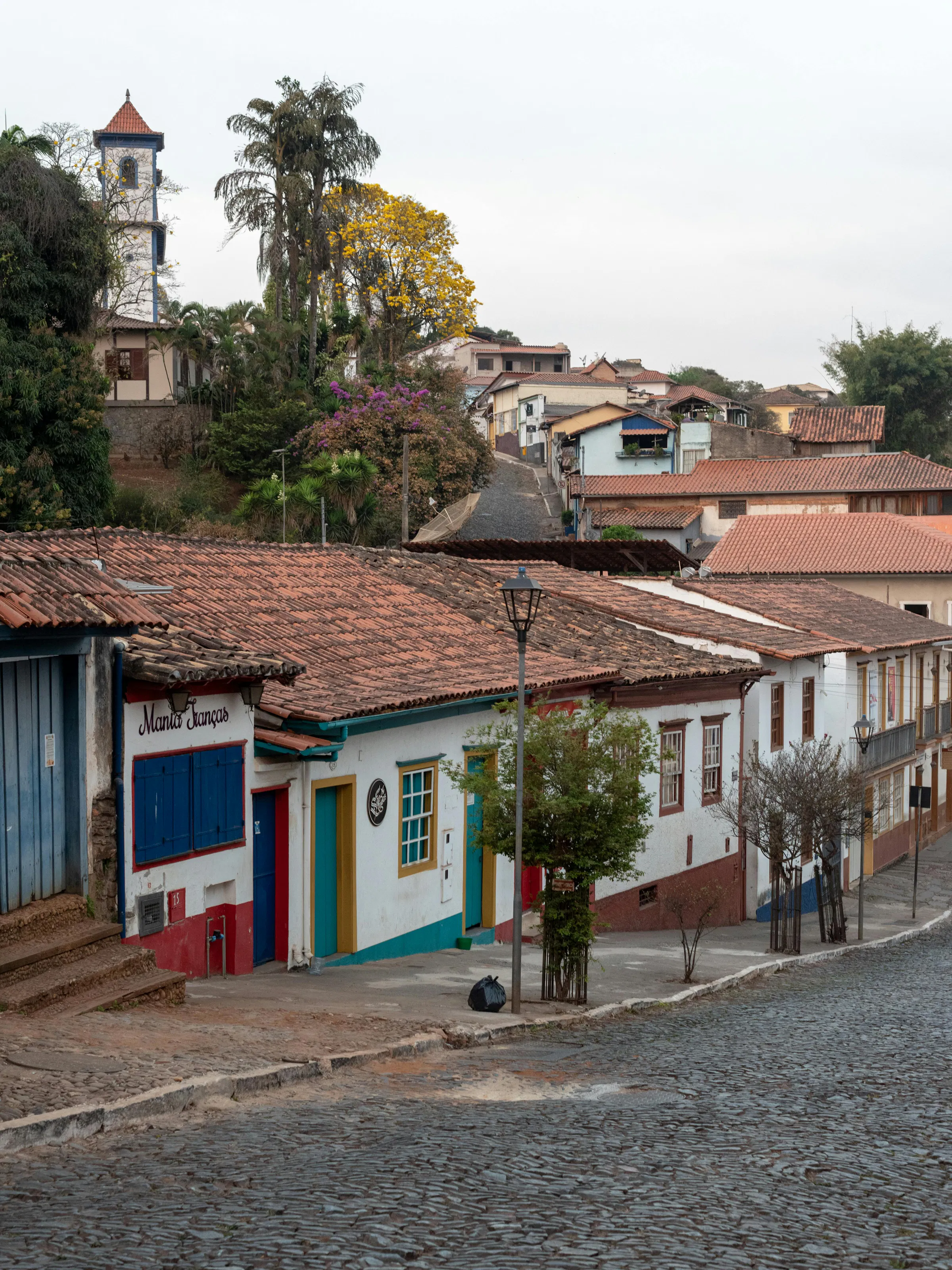 Rolling green hills and a valley town nestle beneath overcast skies in Minas Gerais, Brazil.
