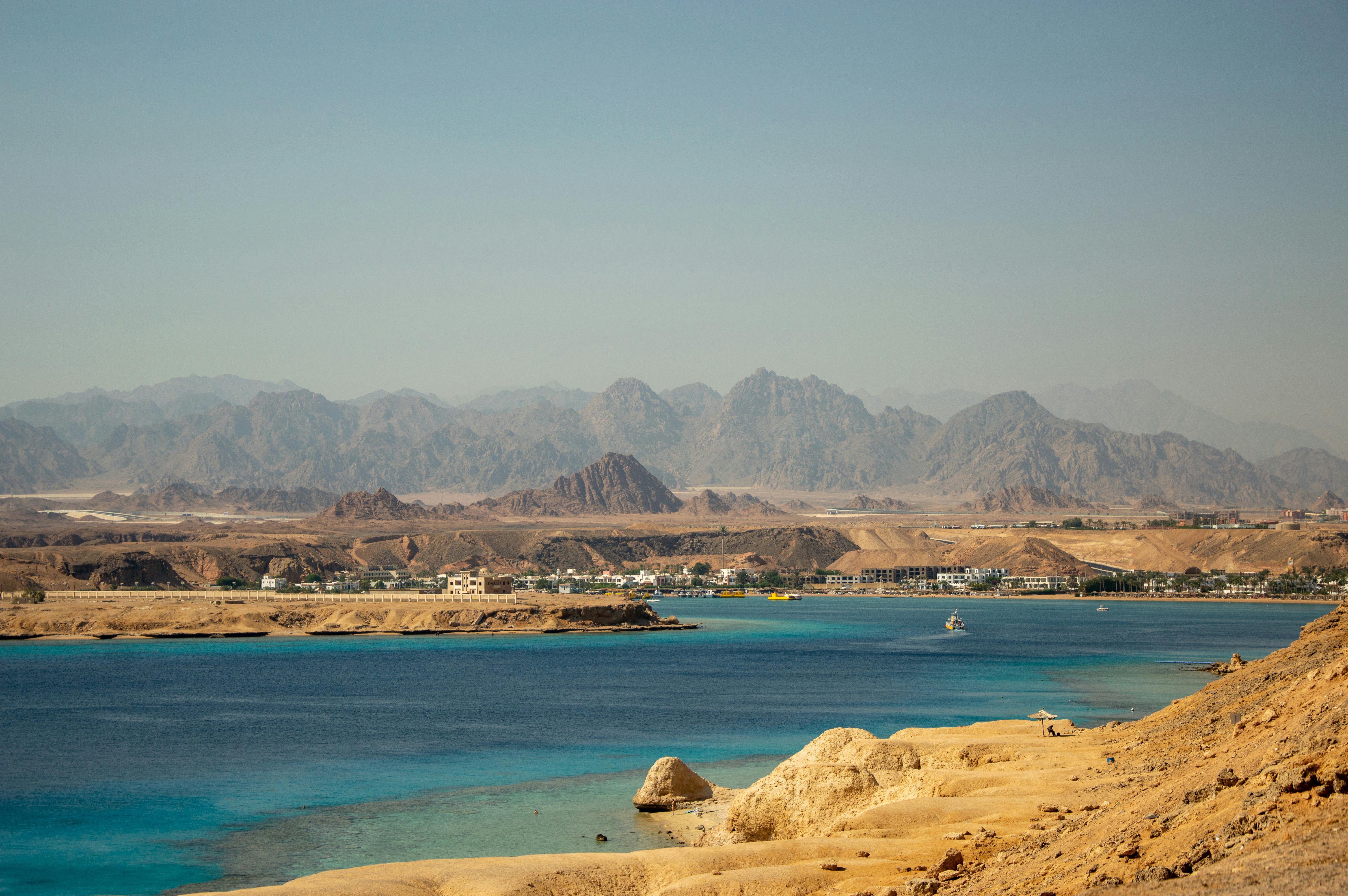 A scuba diver descends through clear blue water toward a coral reef in Egypt's Red Sea.