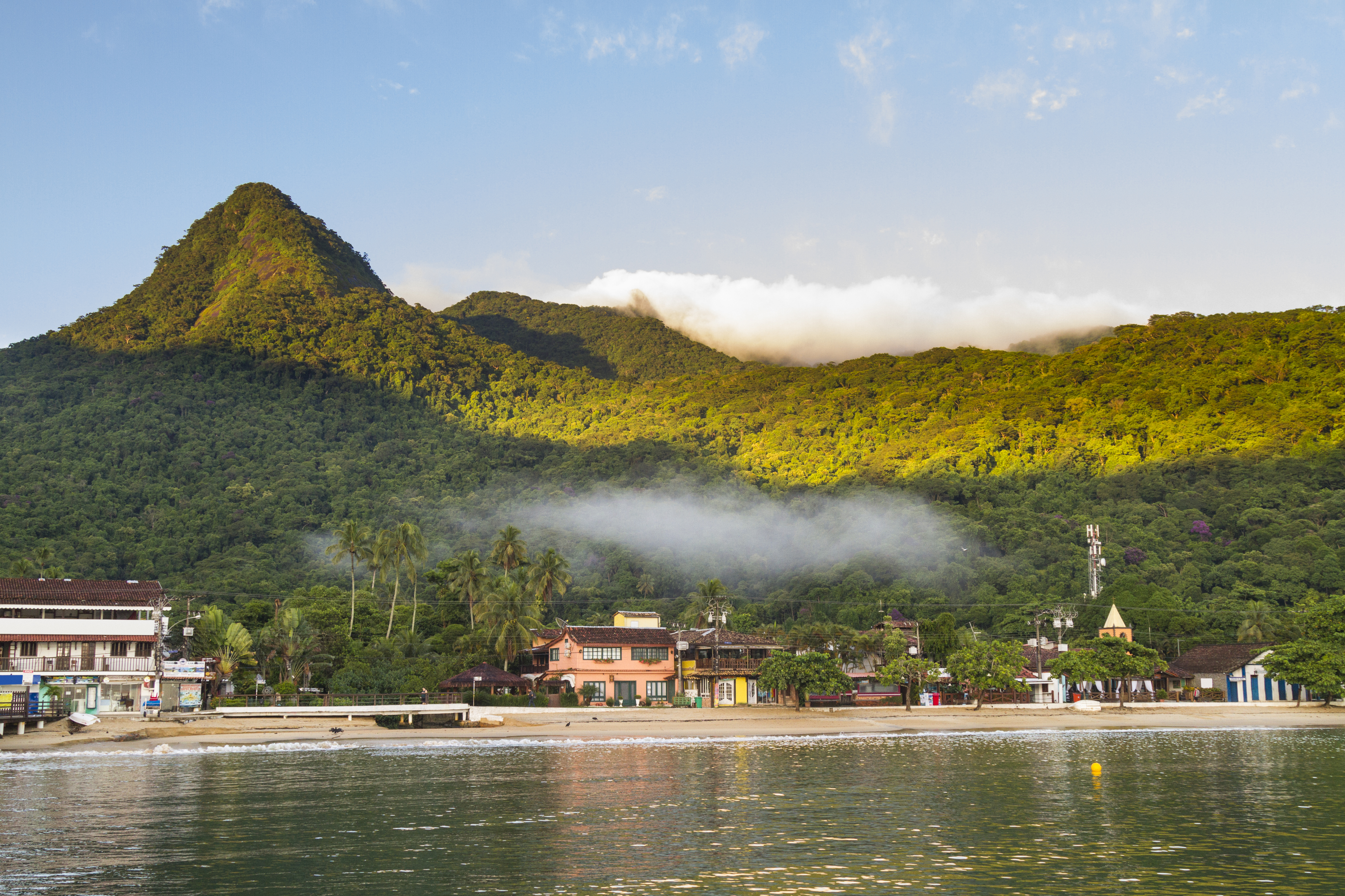 A densely forested green island rises sharply from the calm turquoise sea near Ilha Grande.